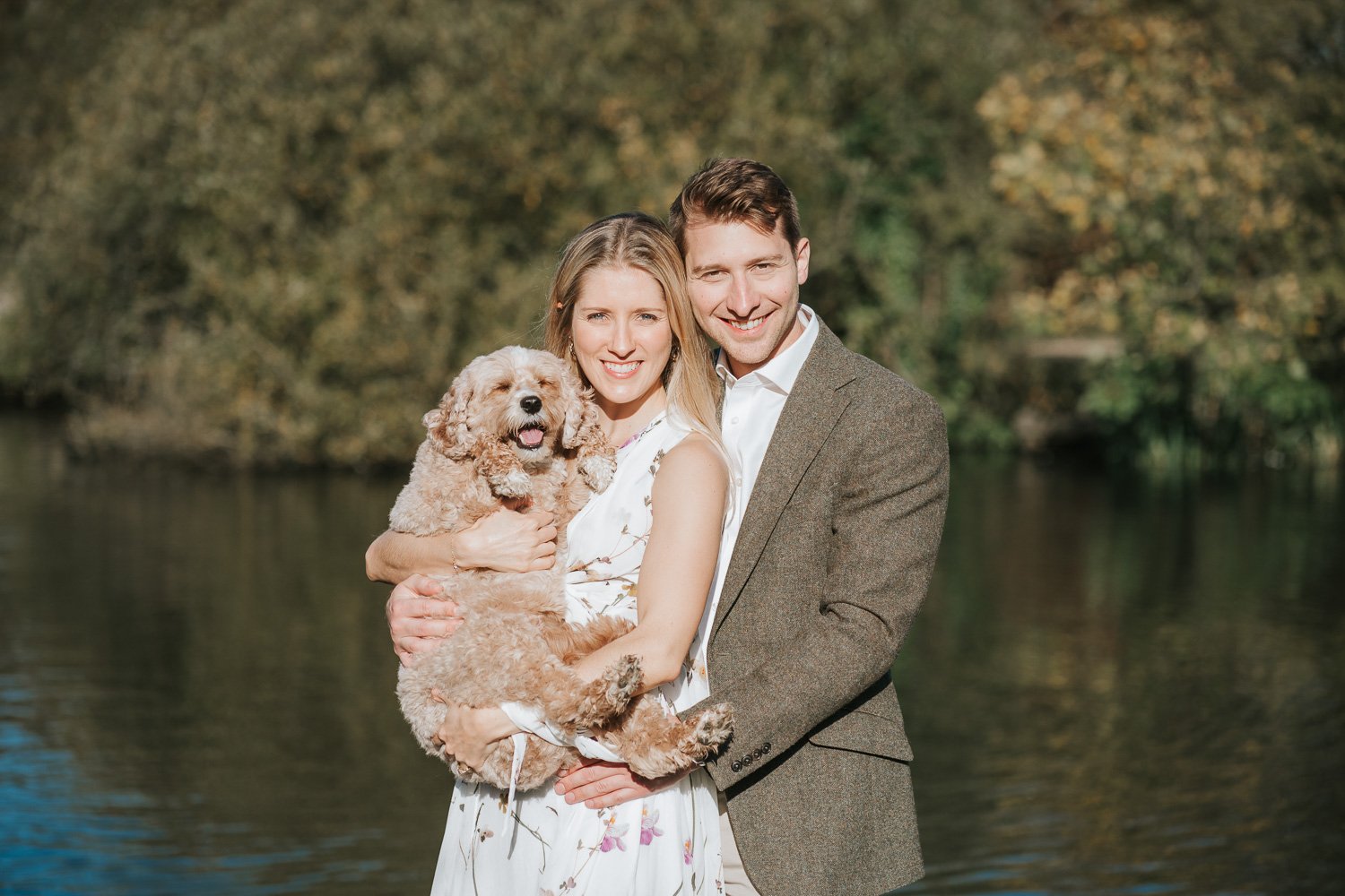  Newly engaged couple Michael and Caroline standing together with their dog by the lake on Wandsworth Common in South West London. 