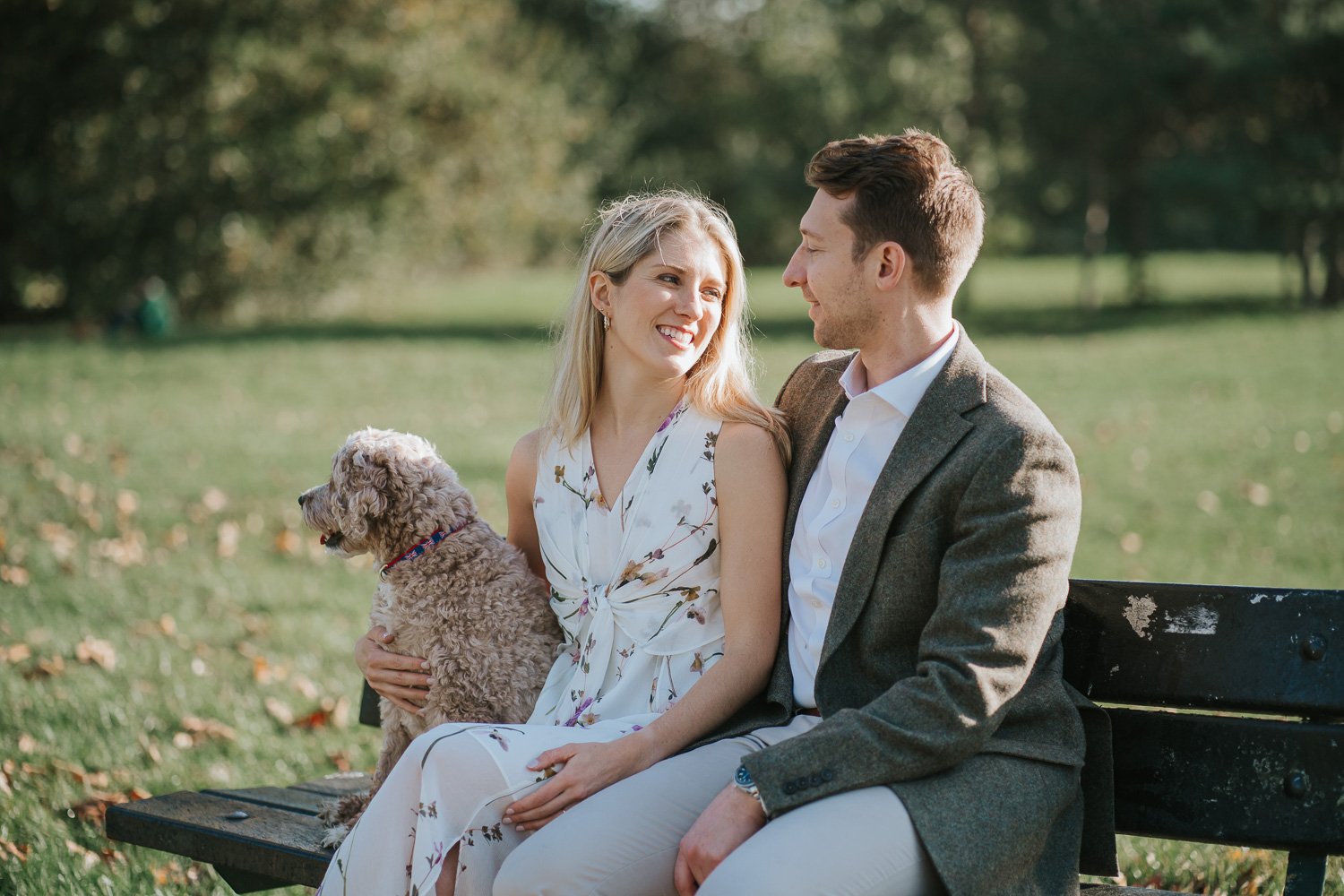  Newly engaged couple Michael and Caroline sitting together with their dog by the lake on Wandsworth Common in South West London. 