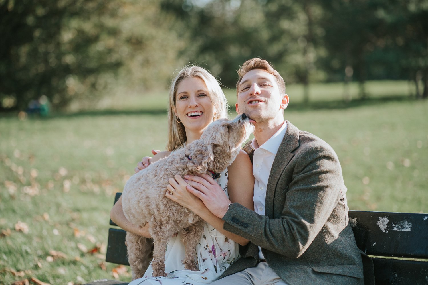  Newly engaged couple Michael and Caroline sitting together with their dog by the lake on Wandsworth Common in South West London. 