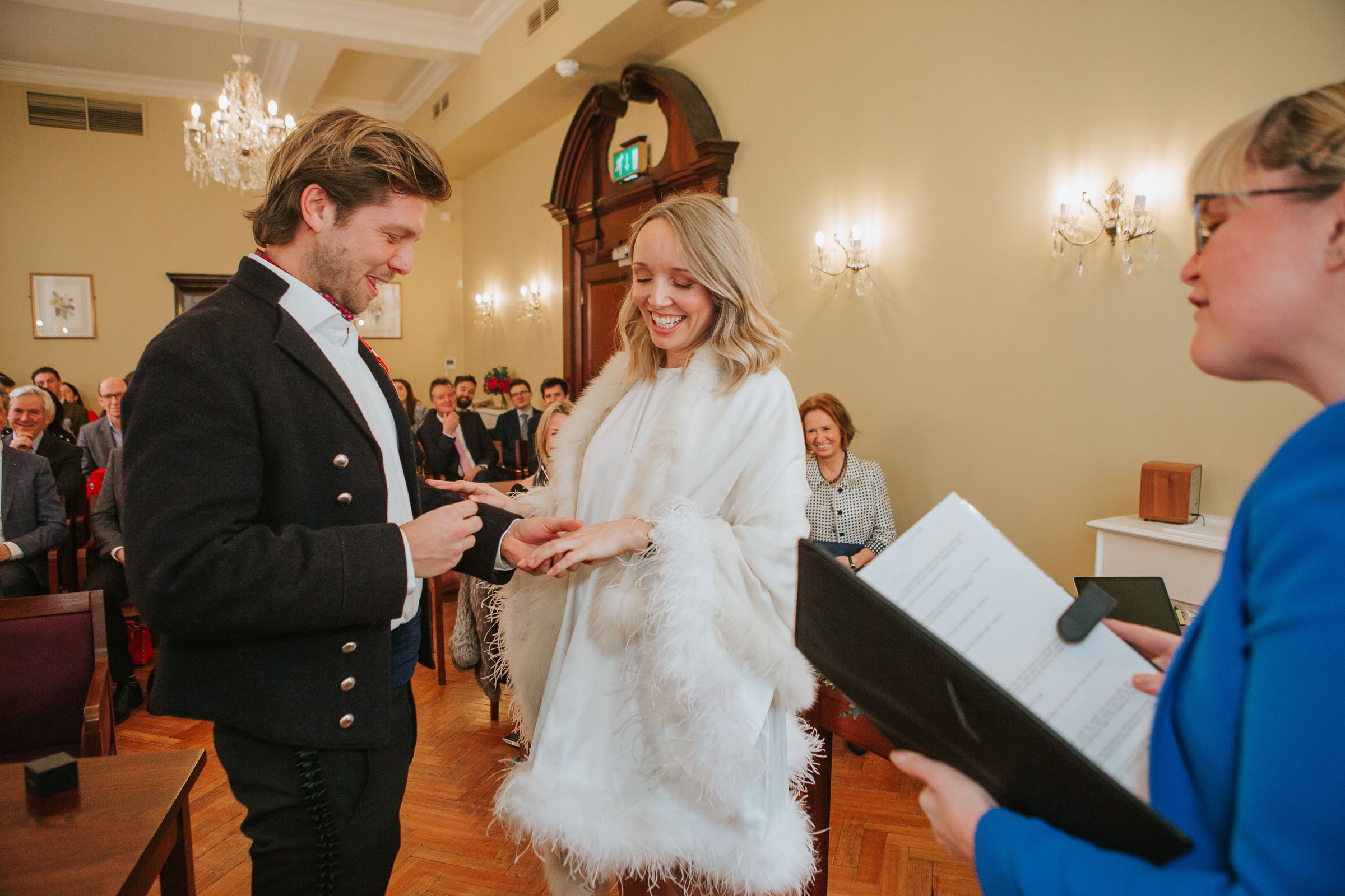  Lizzie and Max exchanging wedding rings in their wedding ceremony in front of their friends and family in The Byron Room at Chelsea Old Town Hall.  