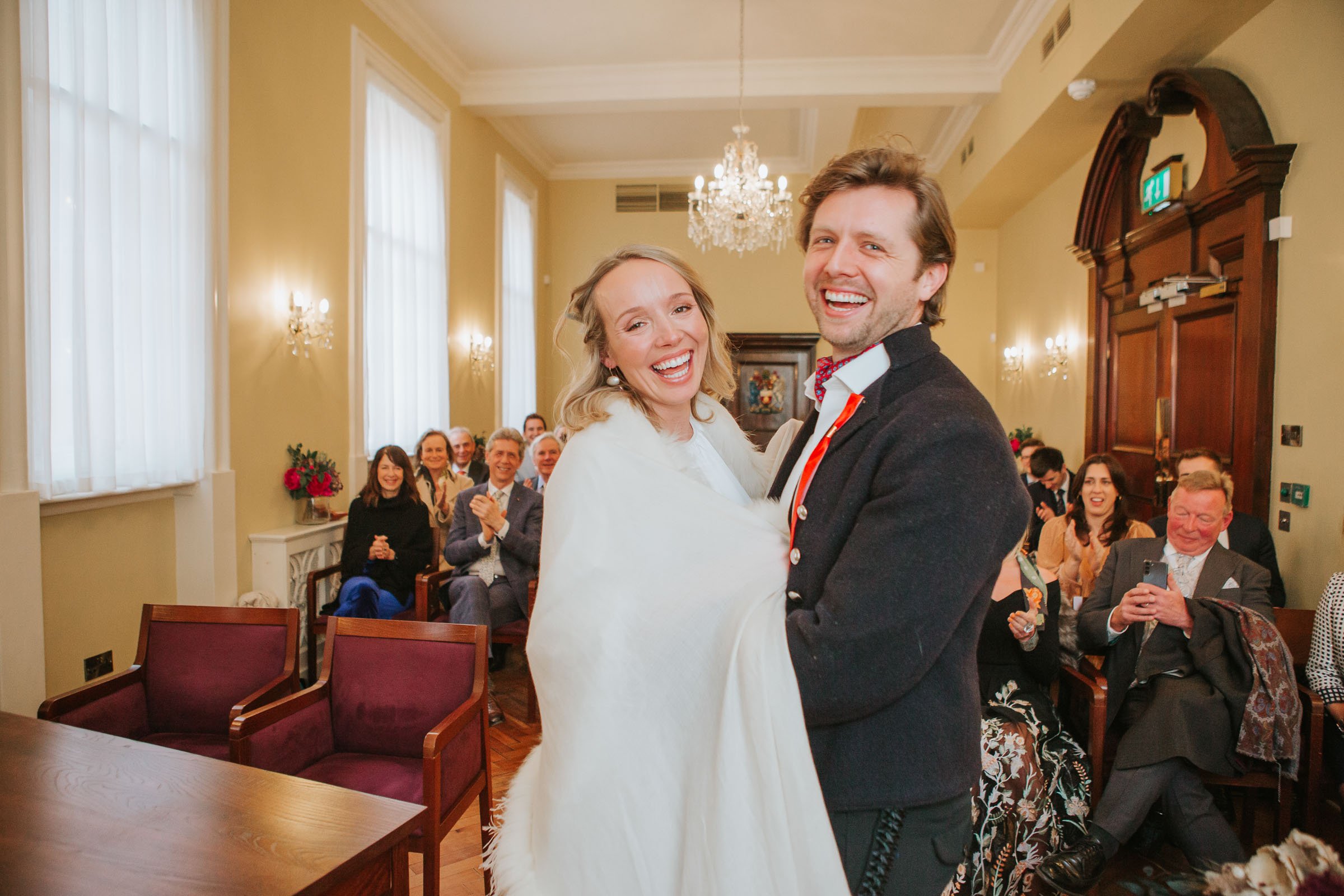  Newly married Lizzie and Max standing in front of their friends and family in The Byron Room at Chelsea Old Town Hall.  