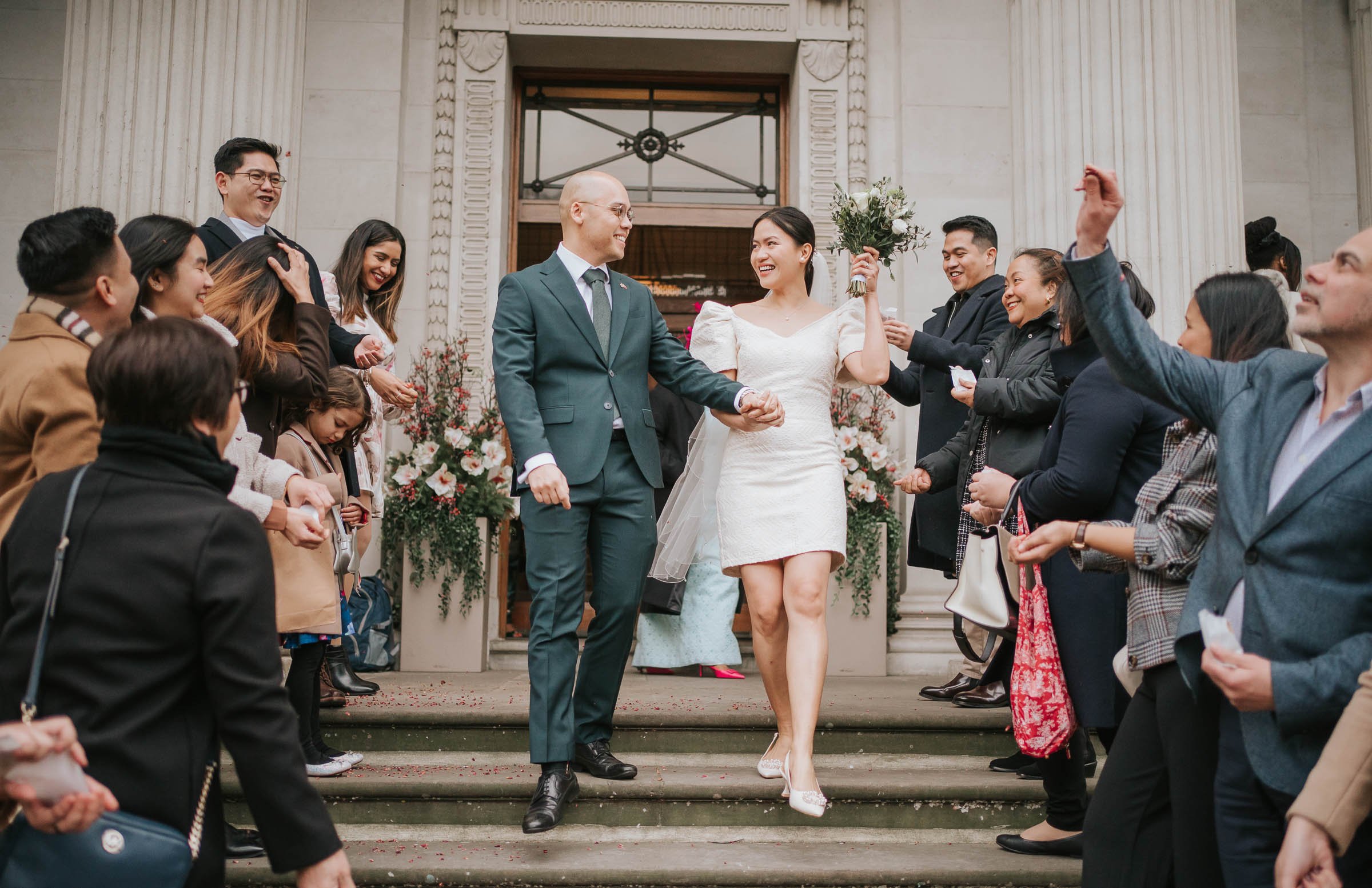  A newly married couple walking down the steps outside their wedding at Marylebone Old Town Hall. 