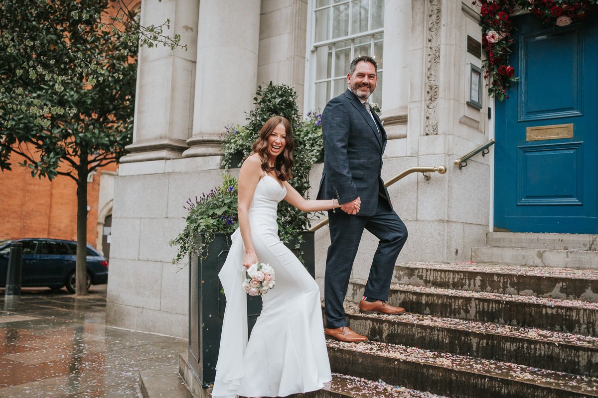  A groom leading his wife up the steps outside Chelsea Old Town Hall. 