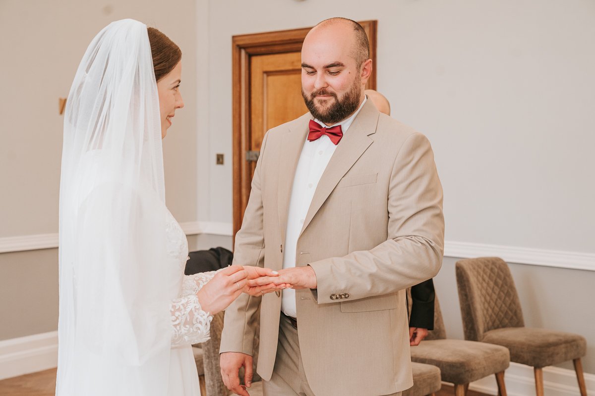  Edina and Zsolt, the bride and groom, face each other and exchange rings as they get married in the wedding ceremony room at Islington Town Hall. 