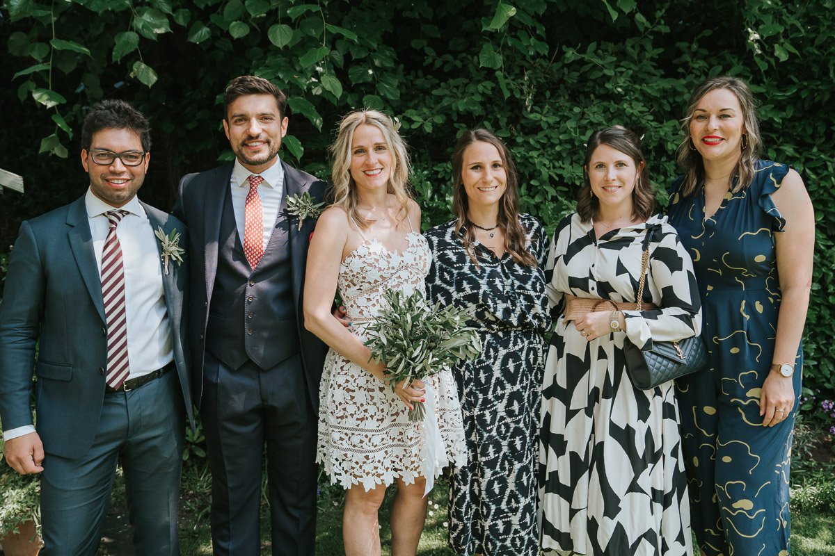  Bride and Groom and friends posing for photographs in the garden of Southwark Register Office. 