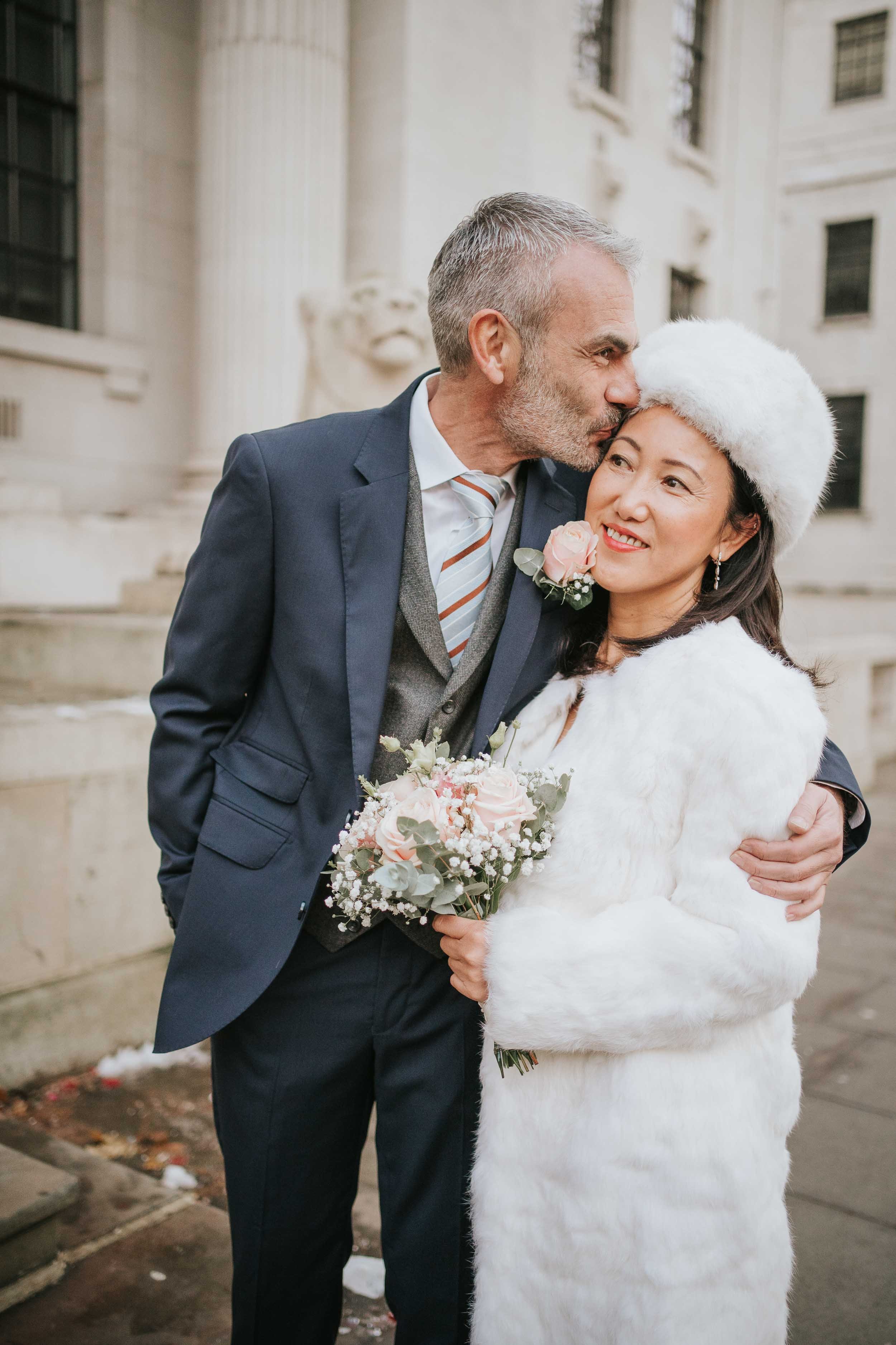  Groom kissing his wife after their wedding at Marylebone Town Hall. 