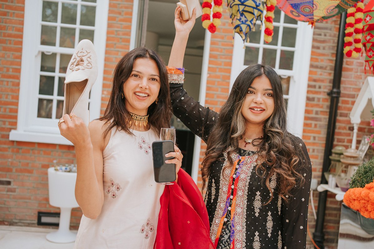  Female guests hold Groom’s shoes at Mehndi Party. 