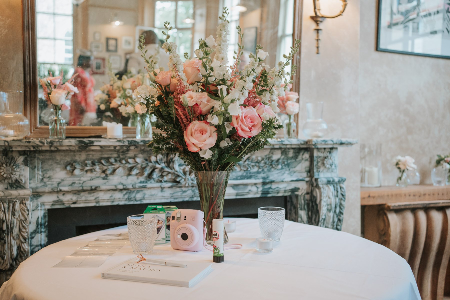  Disposable camera, signing book and large floral display in vase on round table in the Main Dining Room of  The Orange  in Belgravia. 