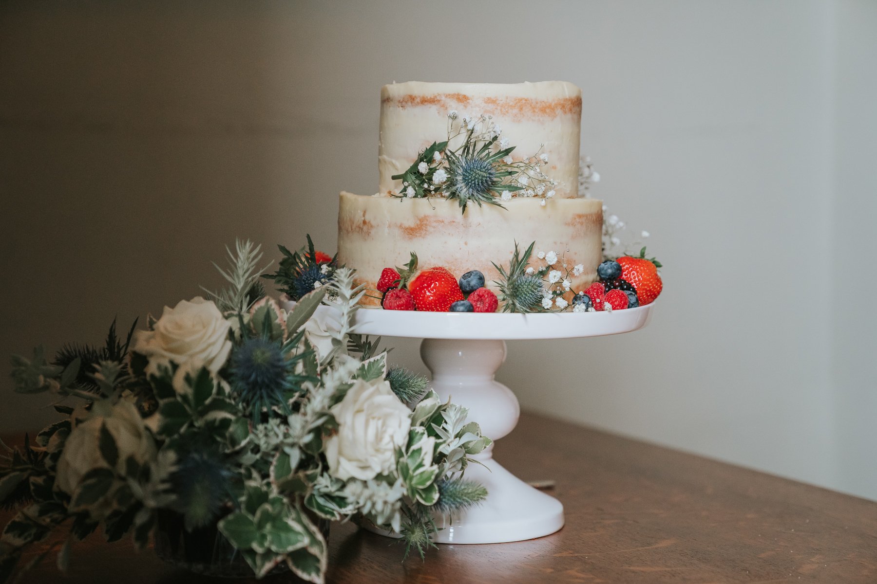  A two-tiered wedding cake decorated with flowers on wooden table. 