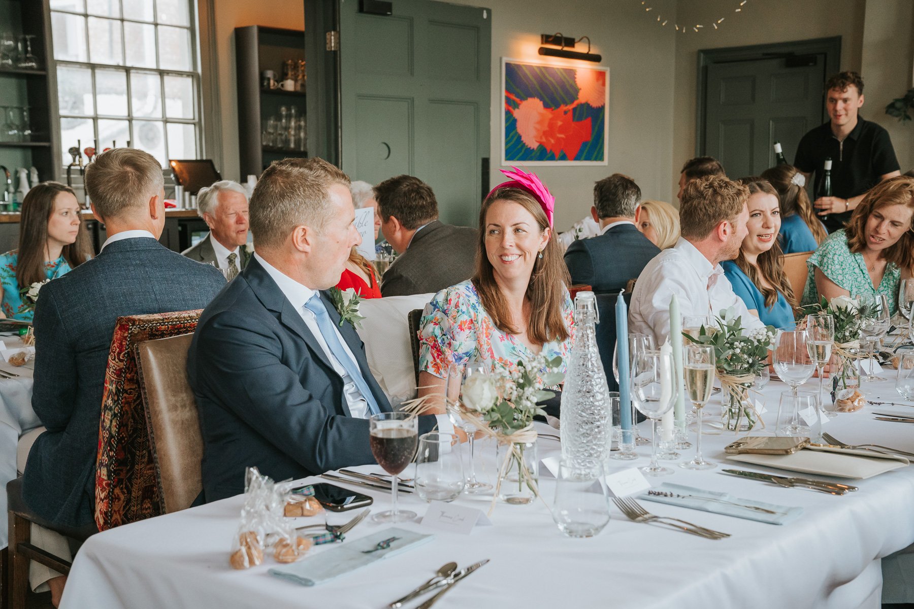  Bride and Groom and guests sit at the dining table in The Melrose Room at The Bulls Head. 