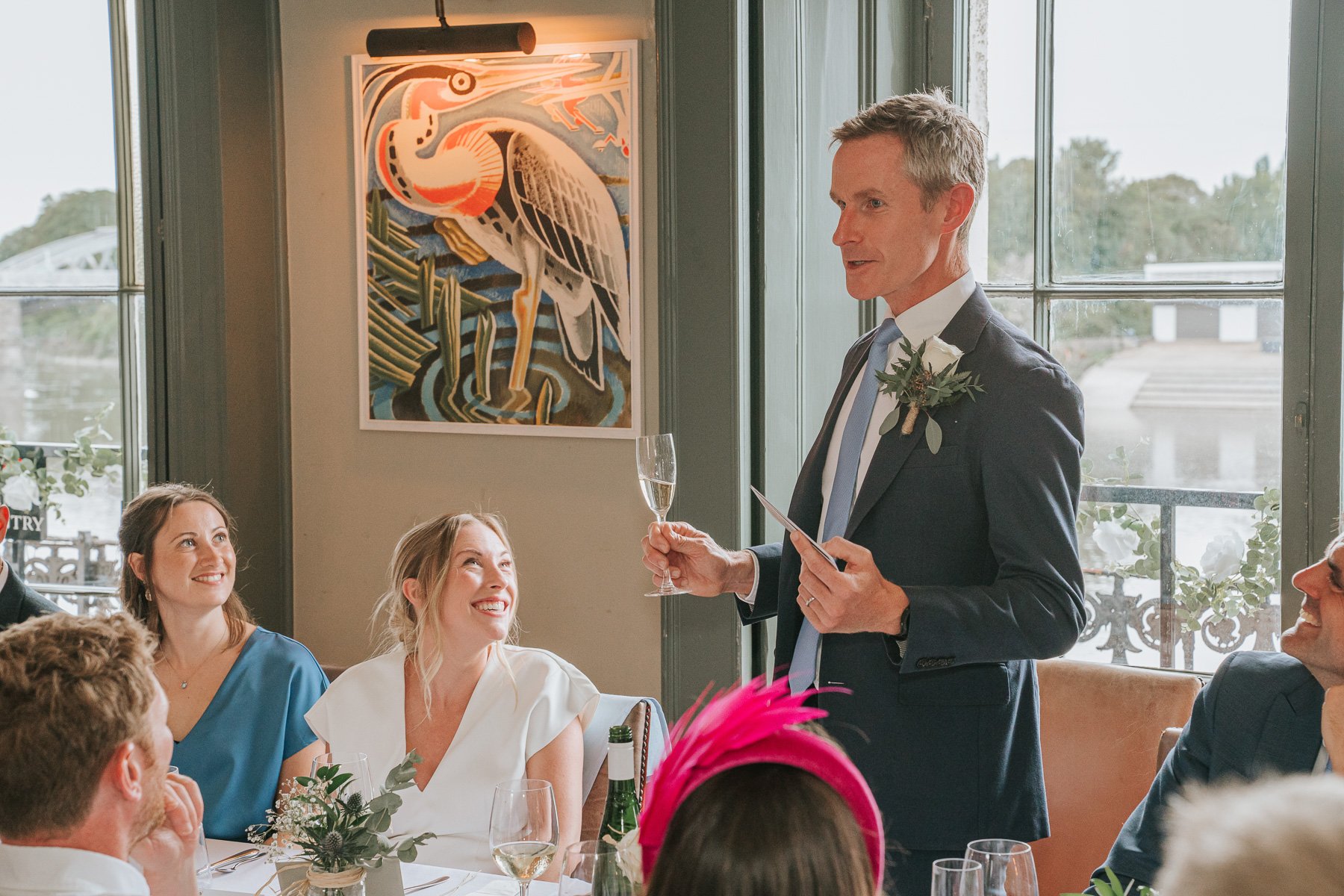  Groom stands at the dining table in The Melrose Room at The Bulls Head and gives speech. 