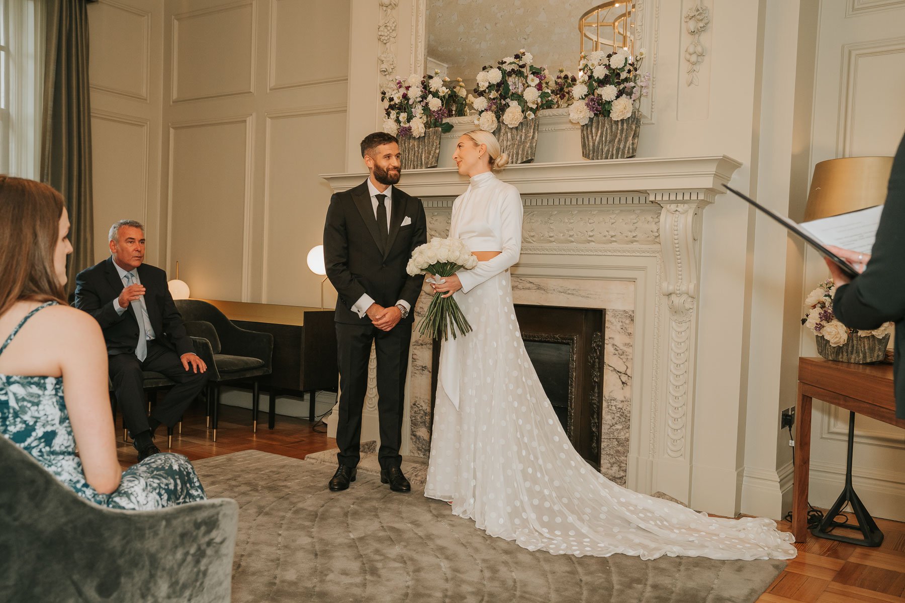  Bride and groom stand in front of friends and family on wedding day in pimlico room of marylebone old town hall. 