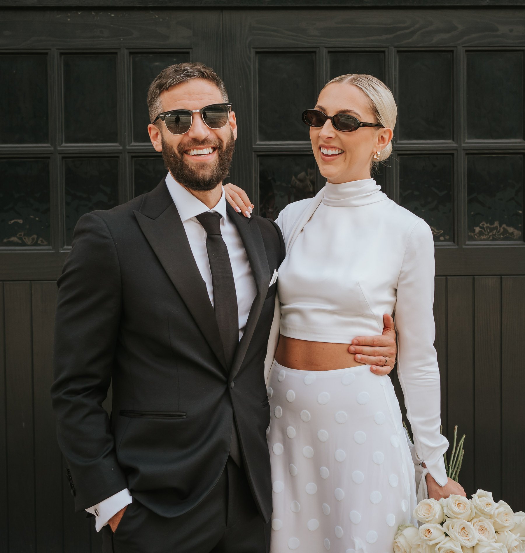  Bride and groom wearing sunglasses pose for camera in street near Marylebone Town Hall. 