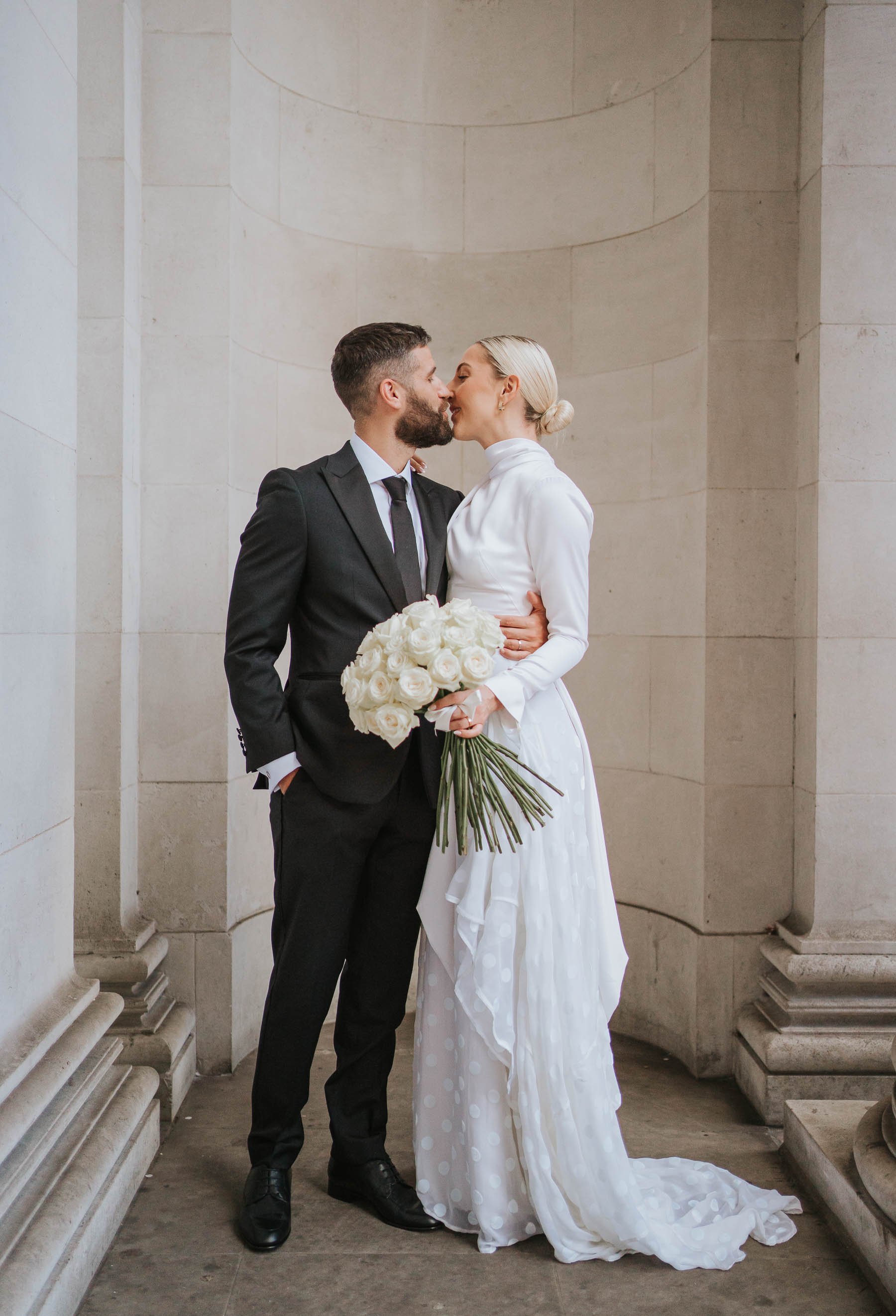  Just married Justin and Abbie kiss between the columns outside the old marylebone town hall. 