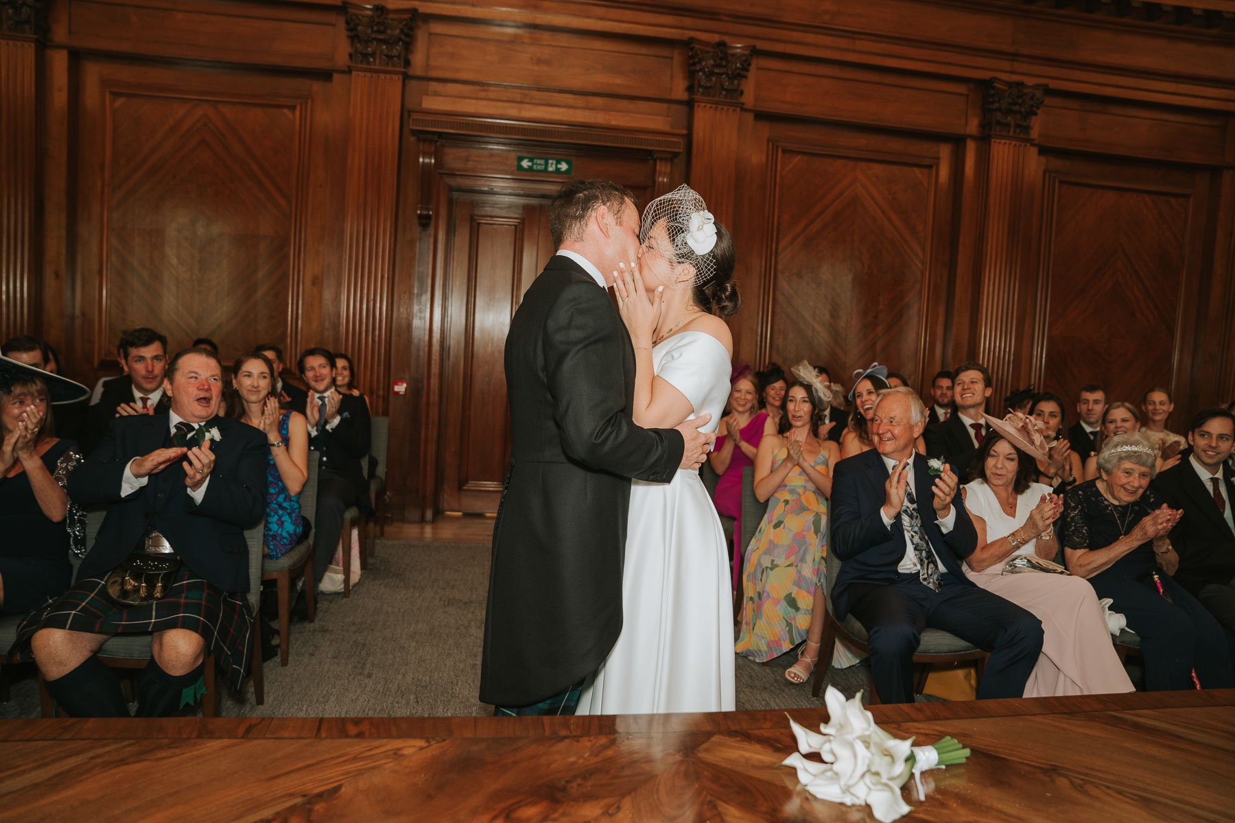  Bride and groom kiss in The Westminster room at Marylebone Town Hall, in front of their family and friends. 