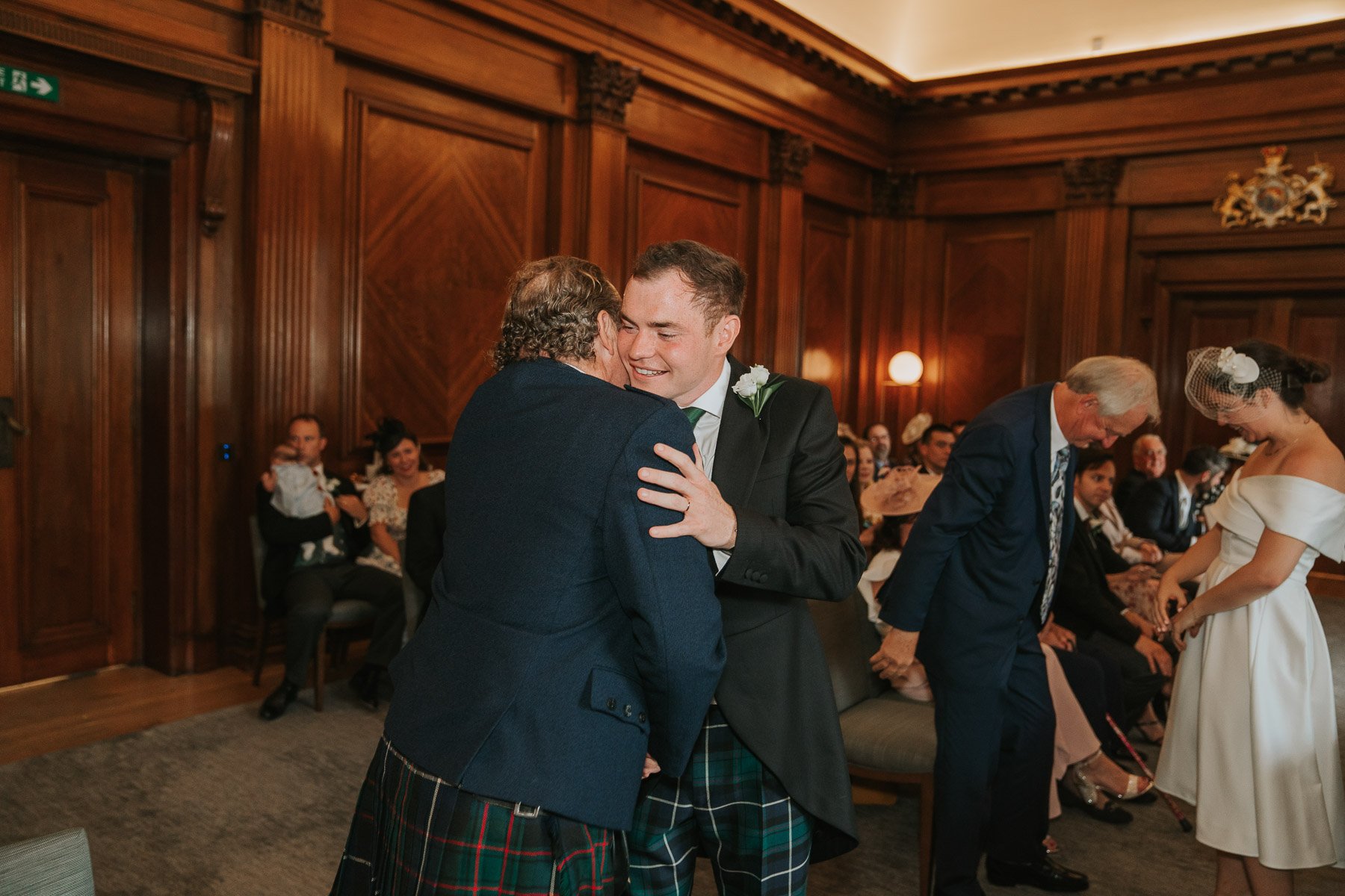  Groom hugs dad after wedding in The Westminster room at Marylebone Town Hall. 
