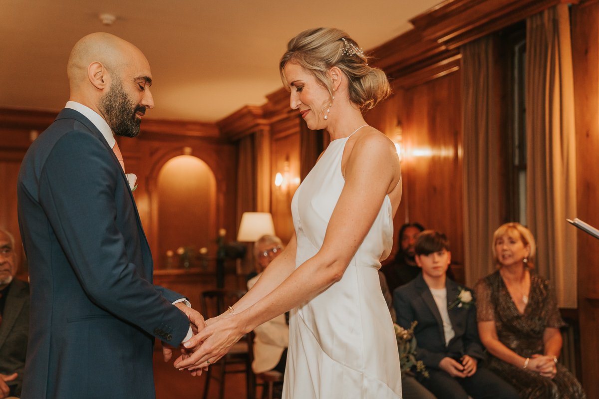  Man and woman hold hands as they exchange wedding vows in the wedding room of Burgh House. 