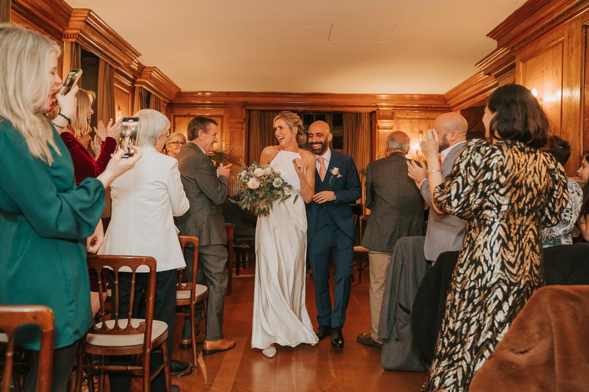  Newly married bride and groom walk between their friends and family following their wedding at Burgh House. 