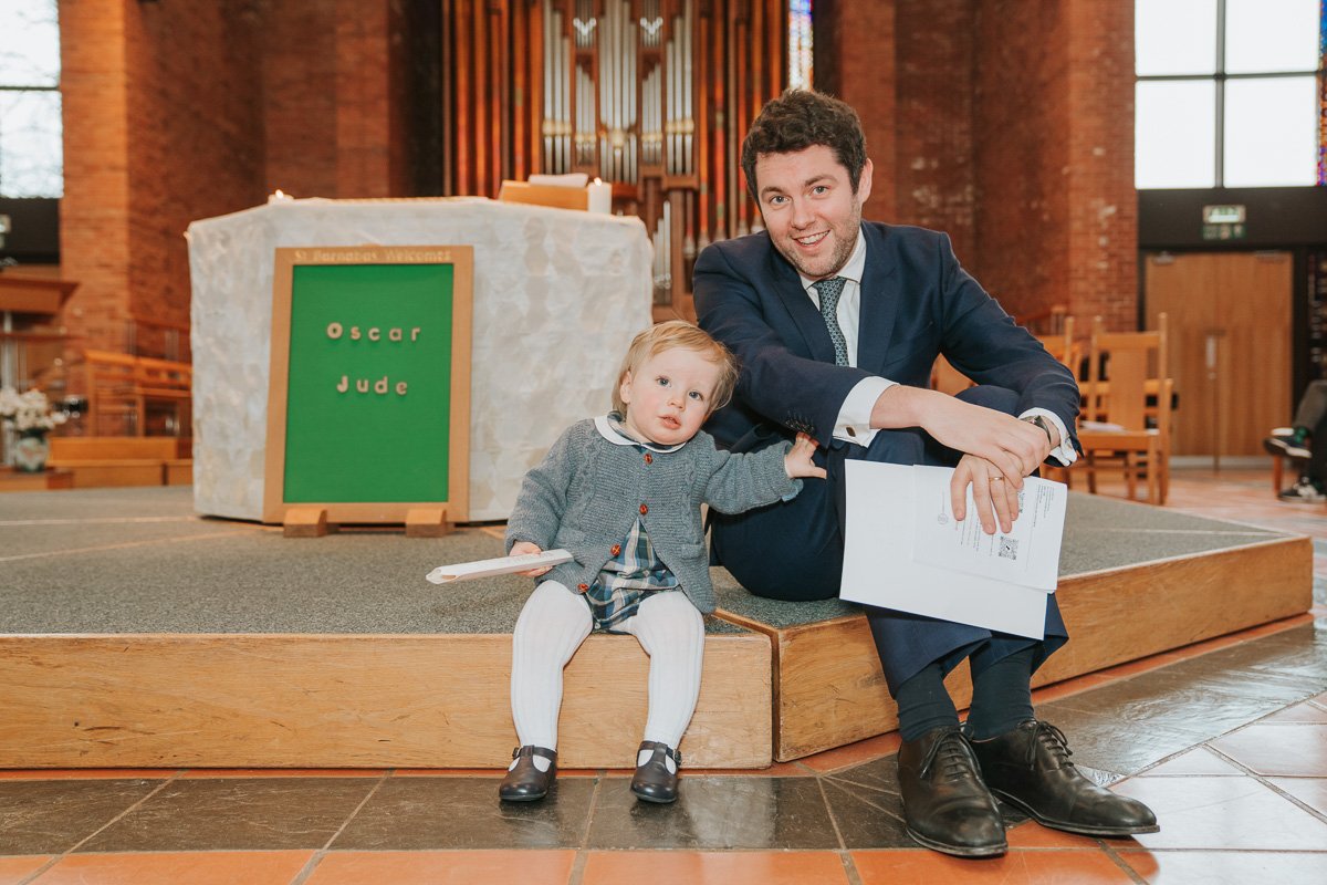  Baby Jude and his dad sit down next to each other in front of the font. 