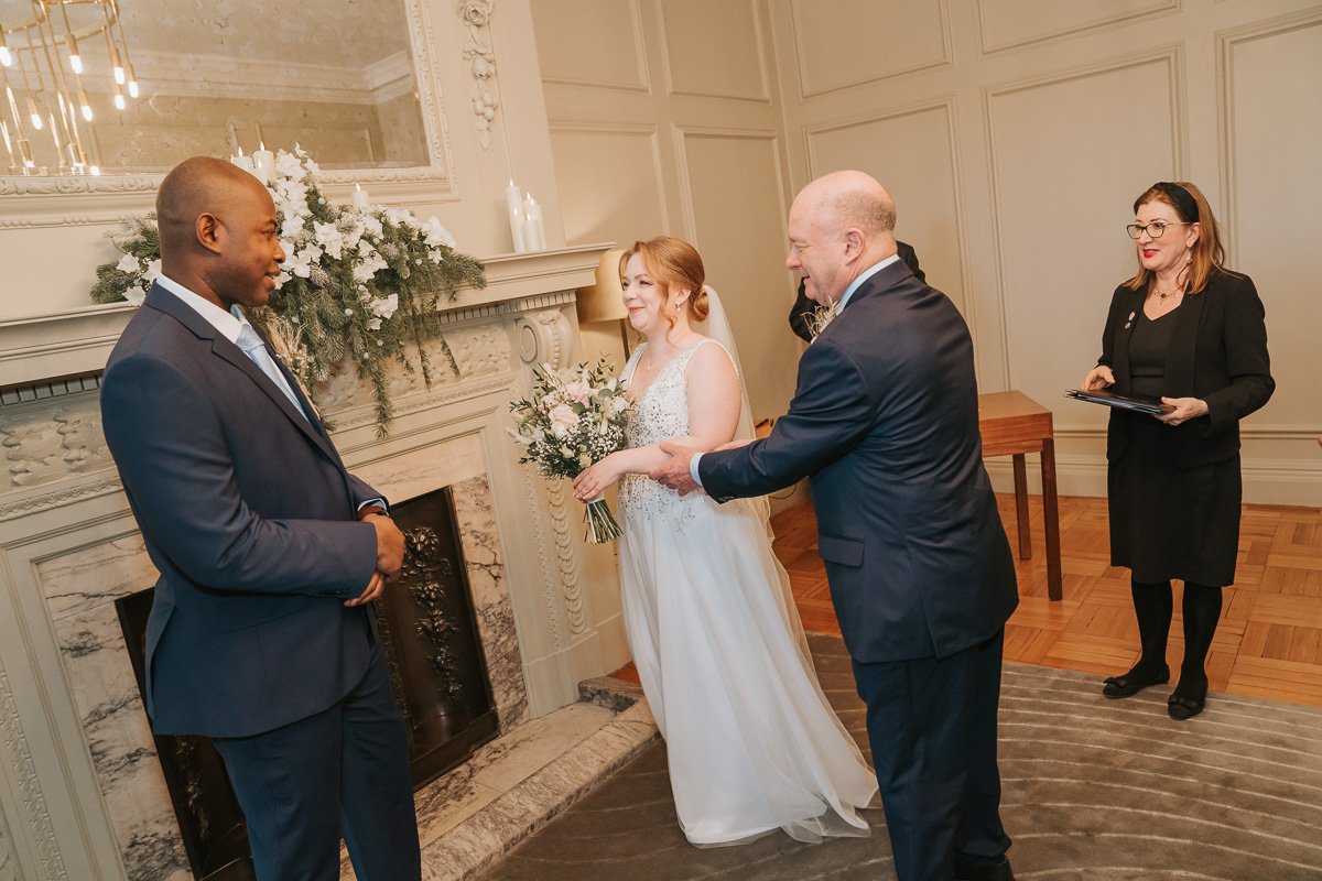  A father hands his daughter over to her future husband at a wedding in Marylebone Town Hall. 