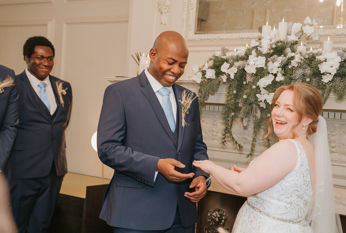  A groom smiles as he places a wedding ring on his bride-to-be inside the pimlico room at the old Marylebone Town Hall. 