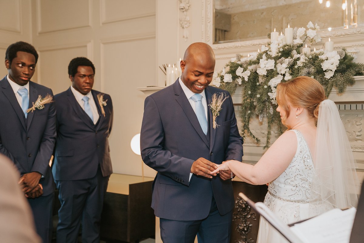  A groom smiles as he places a wedding ring on his bride-to-be inside the pimlico room at the old Marylebone Town Hall. 