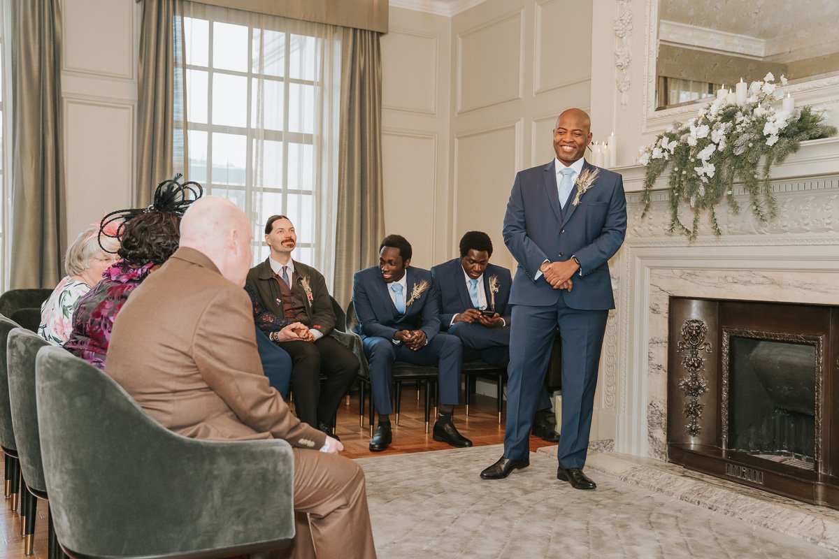  A groom stands smiling at his friends and family in the pimlico room at marylebone town hall. 