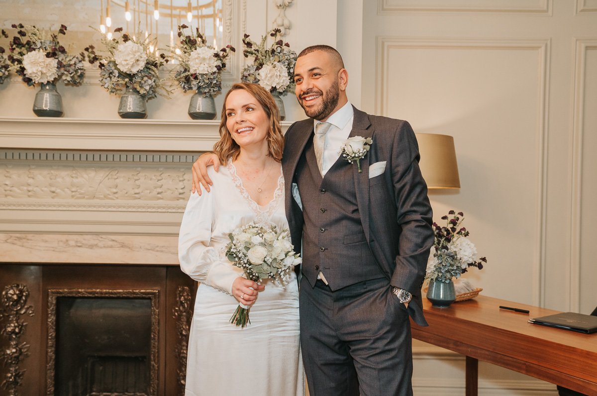  Smiling bride and groom stand arm in arm after their wedding at marylebone town hall register office. 