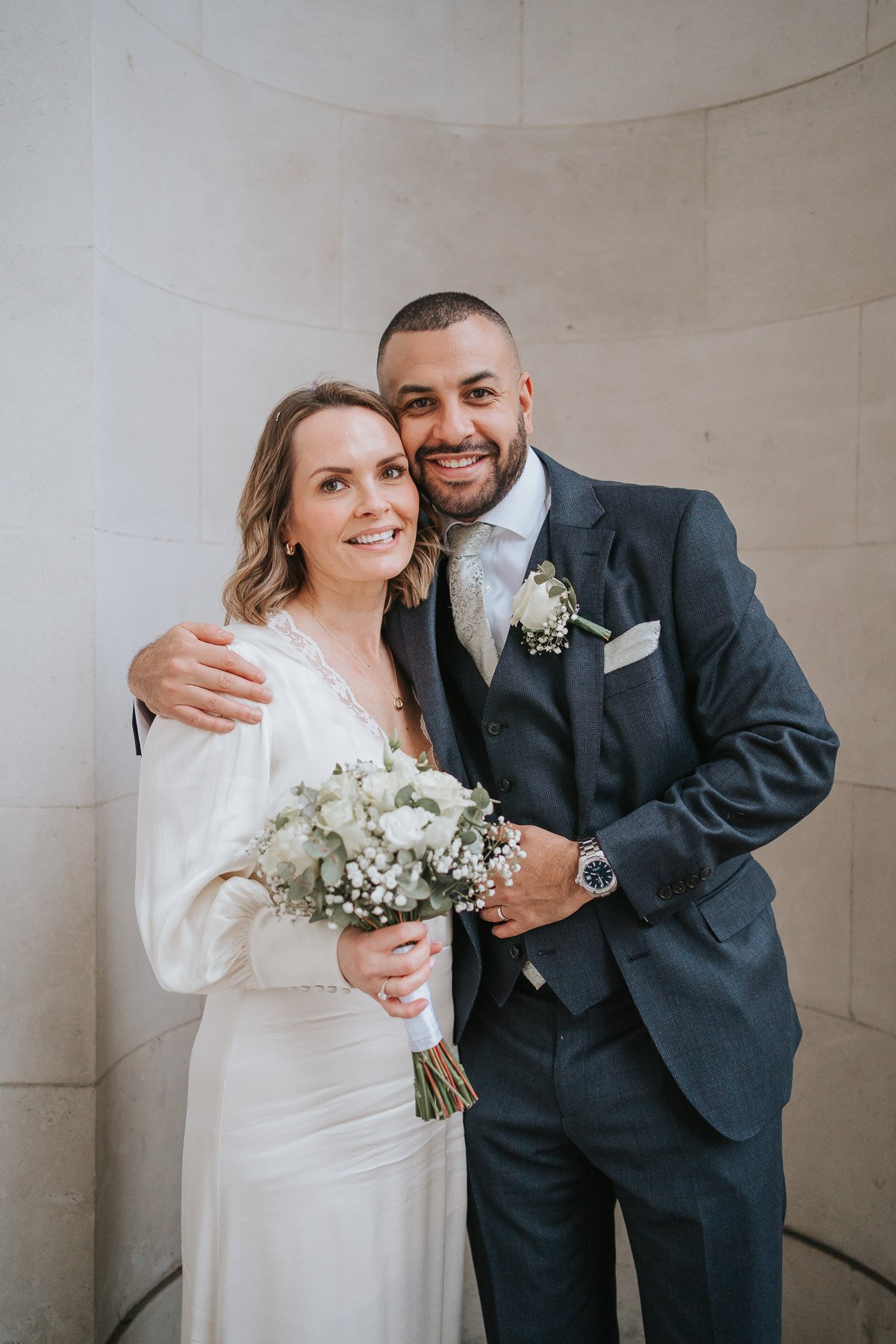  Groom holds his bride outside marylebone town hall register office. 