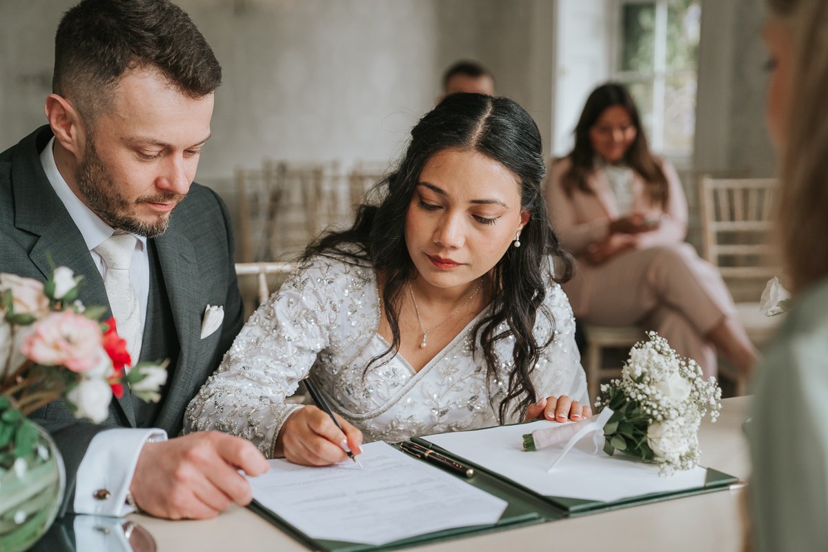  Bride signs register after wedding at morden park house. 
