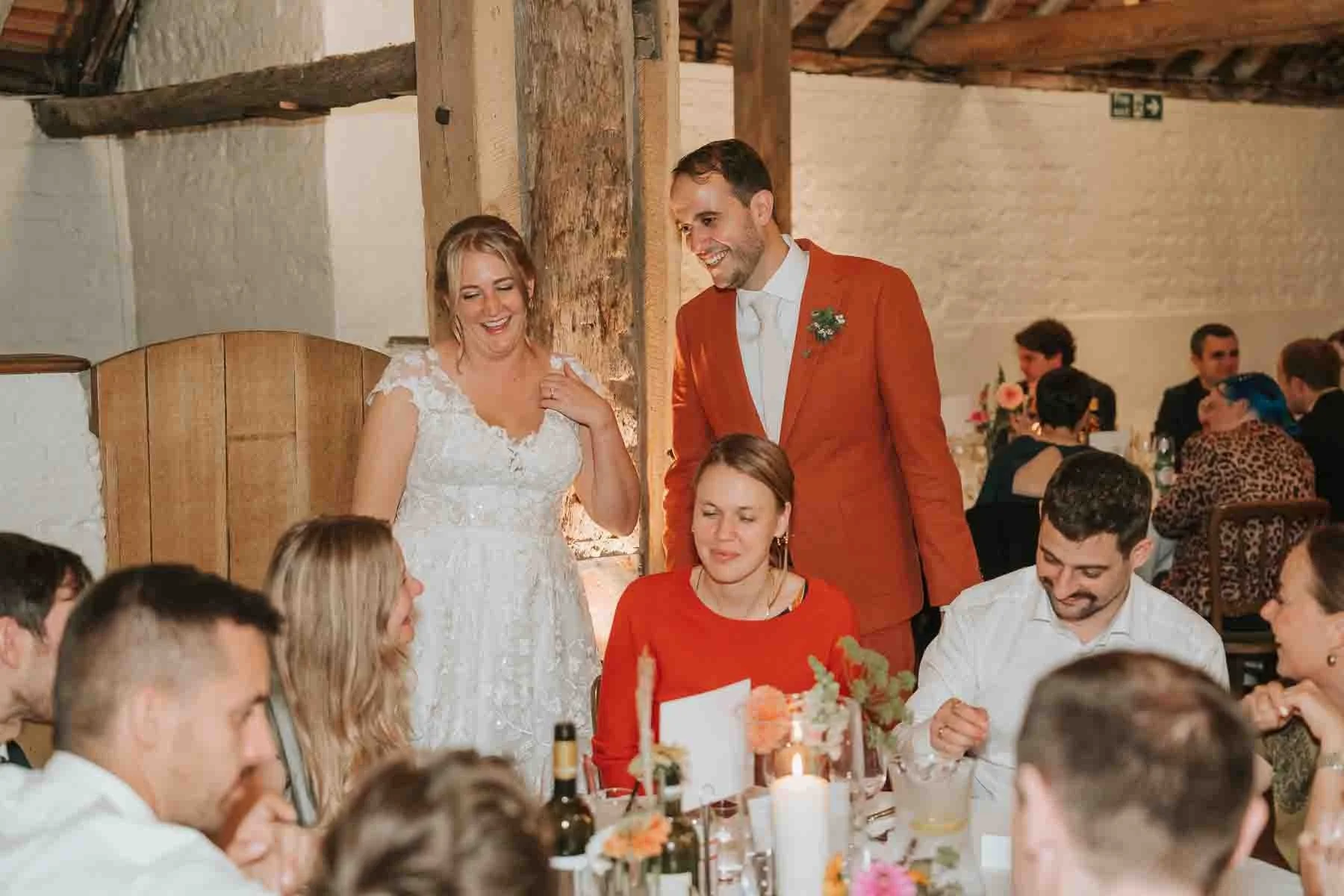  Bride stands with groom while chatting to seated guests at their wedding in Pangdean Old Barn. 