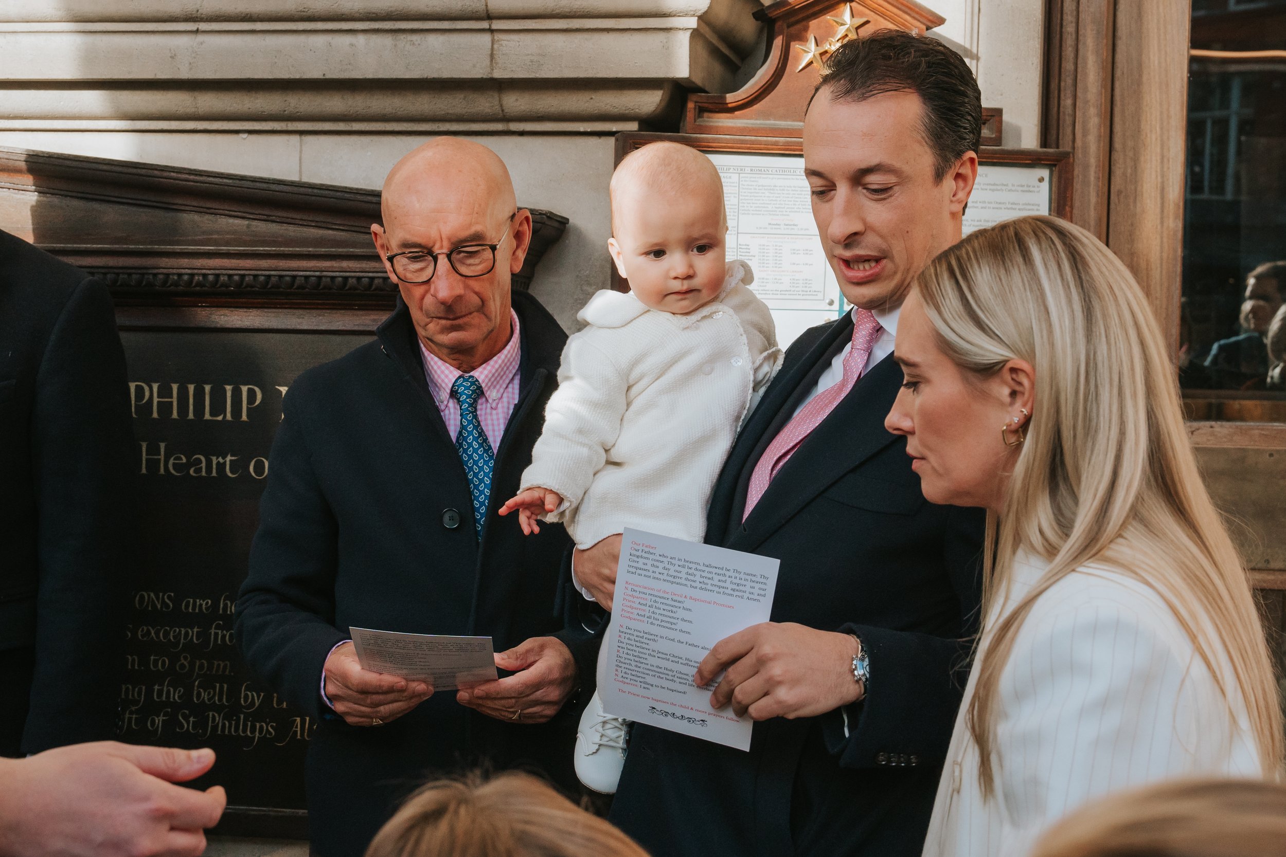  Parents holding their baby in a christening gown inside Brompton Oratory, London 