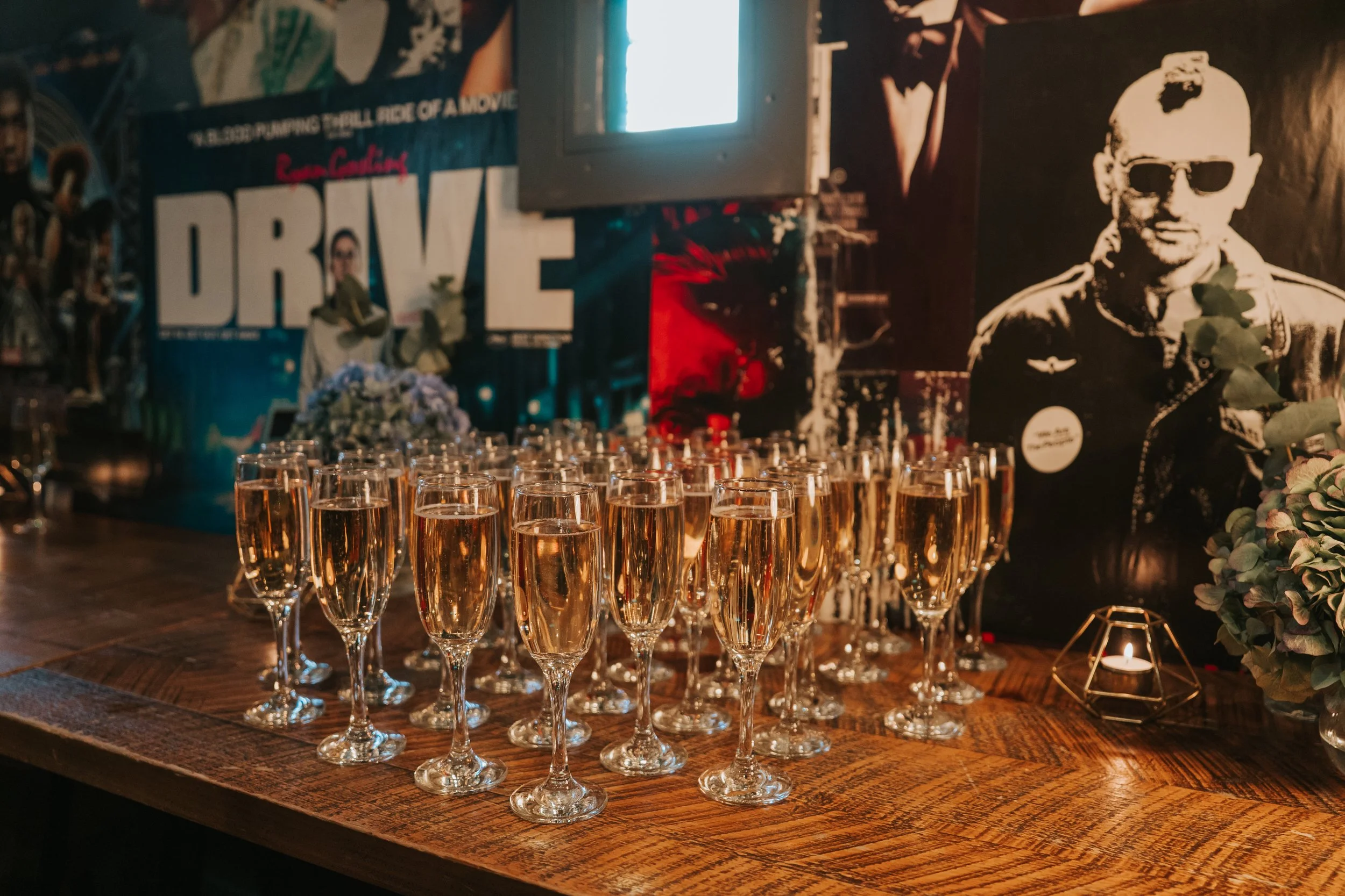   Rows of champagne glasses ready for guests at a Brixton wedding reception inside The Ritzy, surrounded by movie posters.  