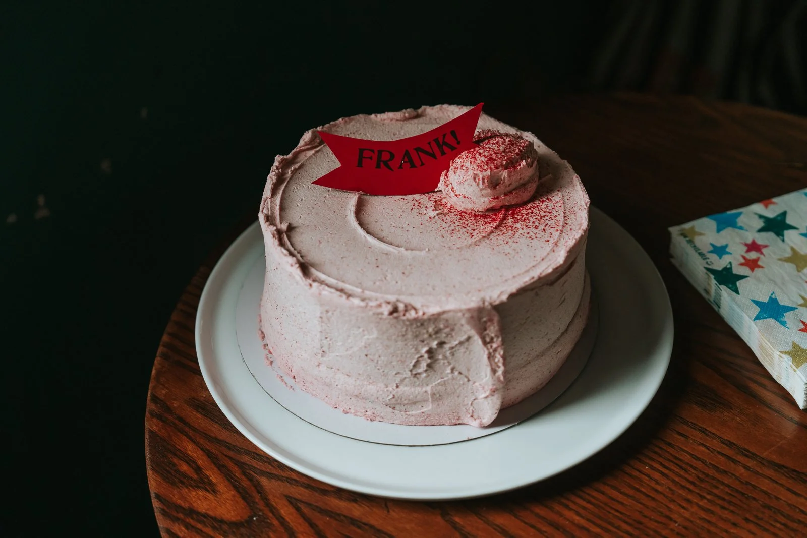  Close-up of a pink buttercream celebration cake with a red name tag on top, ready for the naming day party at The Pembury Tavern. 