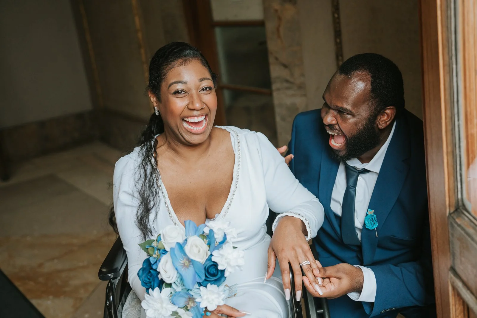   Newlyweds laughing together as the groom holds the bride’s hand to show off her wedding ring, captured just inside Wandsworth Town Hall.  