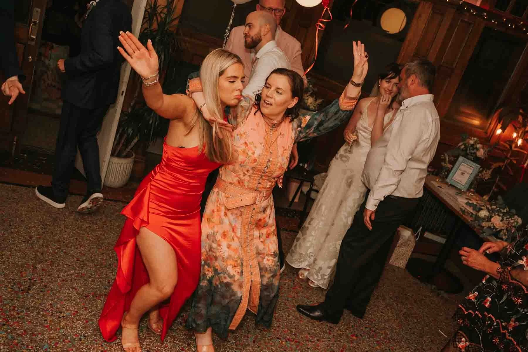  Guests dancing with their arms in the air during a lively London wedding party, captured candidly on the dancefloor. 