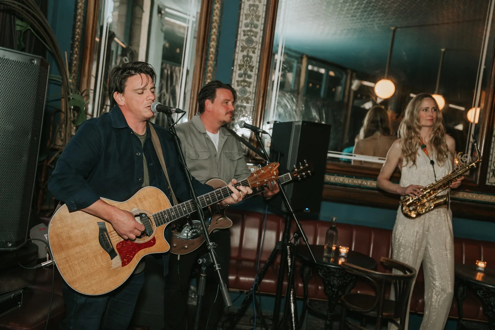  Acoustic musicians singing and playing guitar during a relaxed London pub wedding reception, captured in a candid documentary style. 