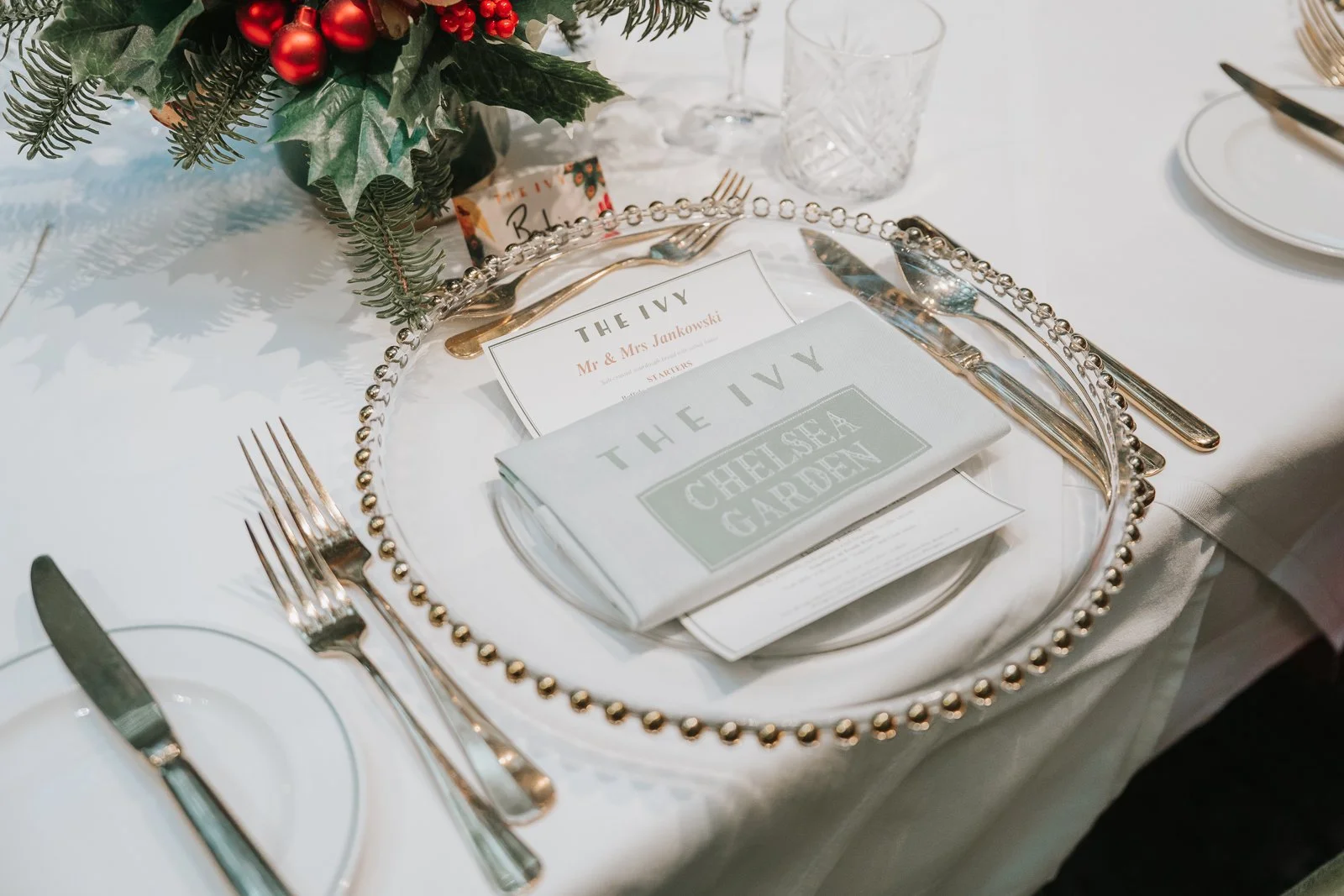  Elegant place setting for a winter wedding in The Glasshouse Room at The Ivy Chelsea Garden, featuring beaded charger plates, The Ivy menus and festive table décor 
