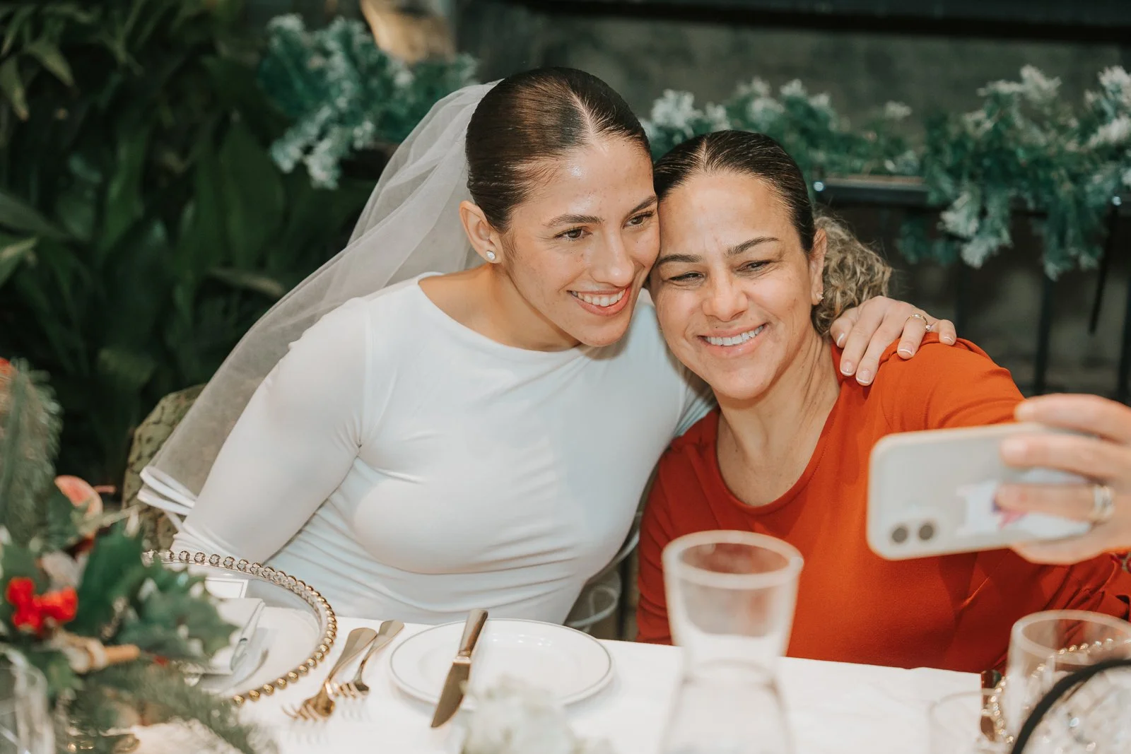  Bride sharing a joyful moment with a family member during a relaxed wedding reception in the Glasshouse Room at The Ivy Chelsea Garden 