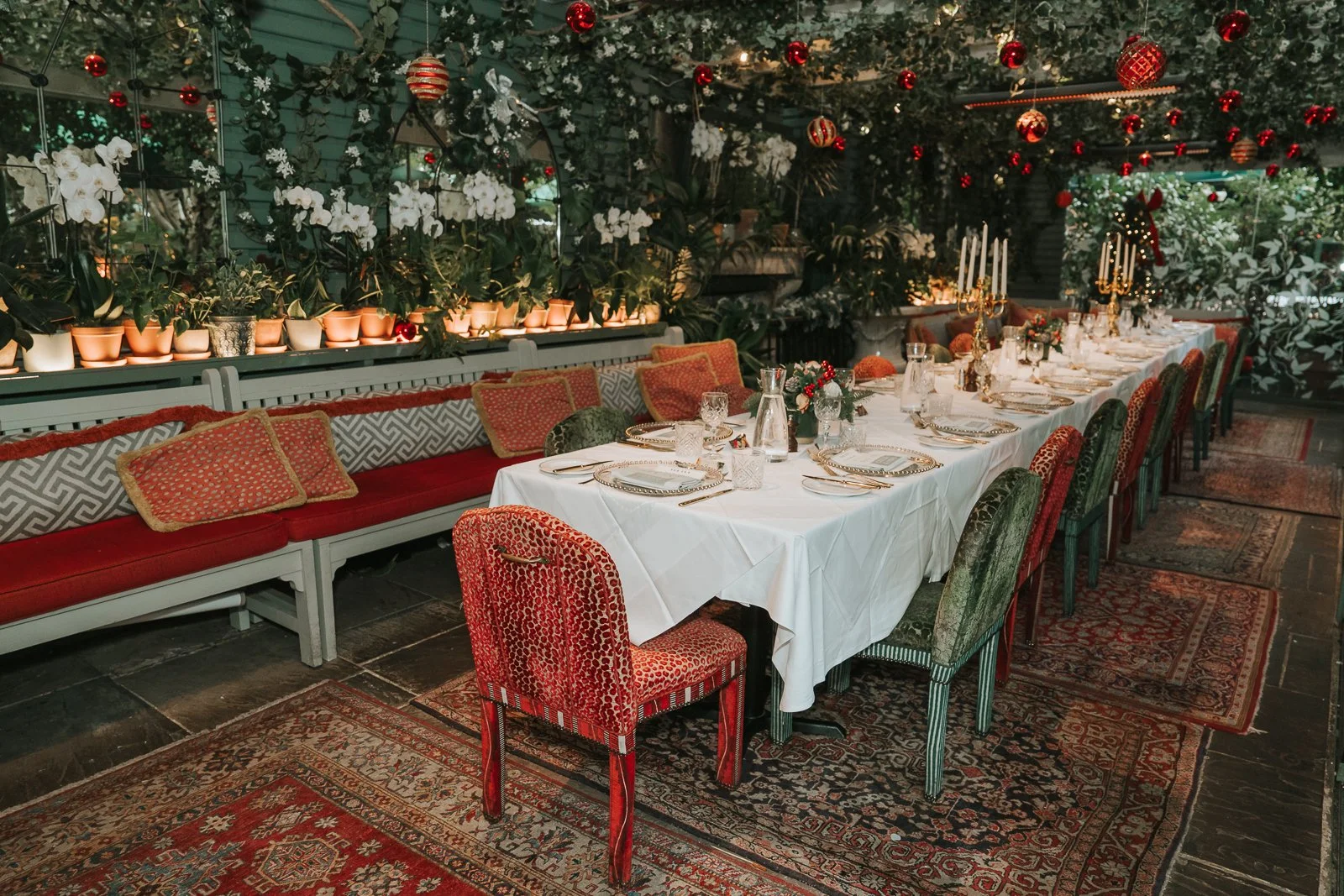  Long festive dining table set for a winter wedding in The Glasshouse Room at The Ivy Chelsea Garden, styled with greenery, candles and elegant place settings 