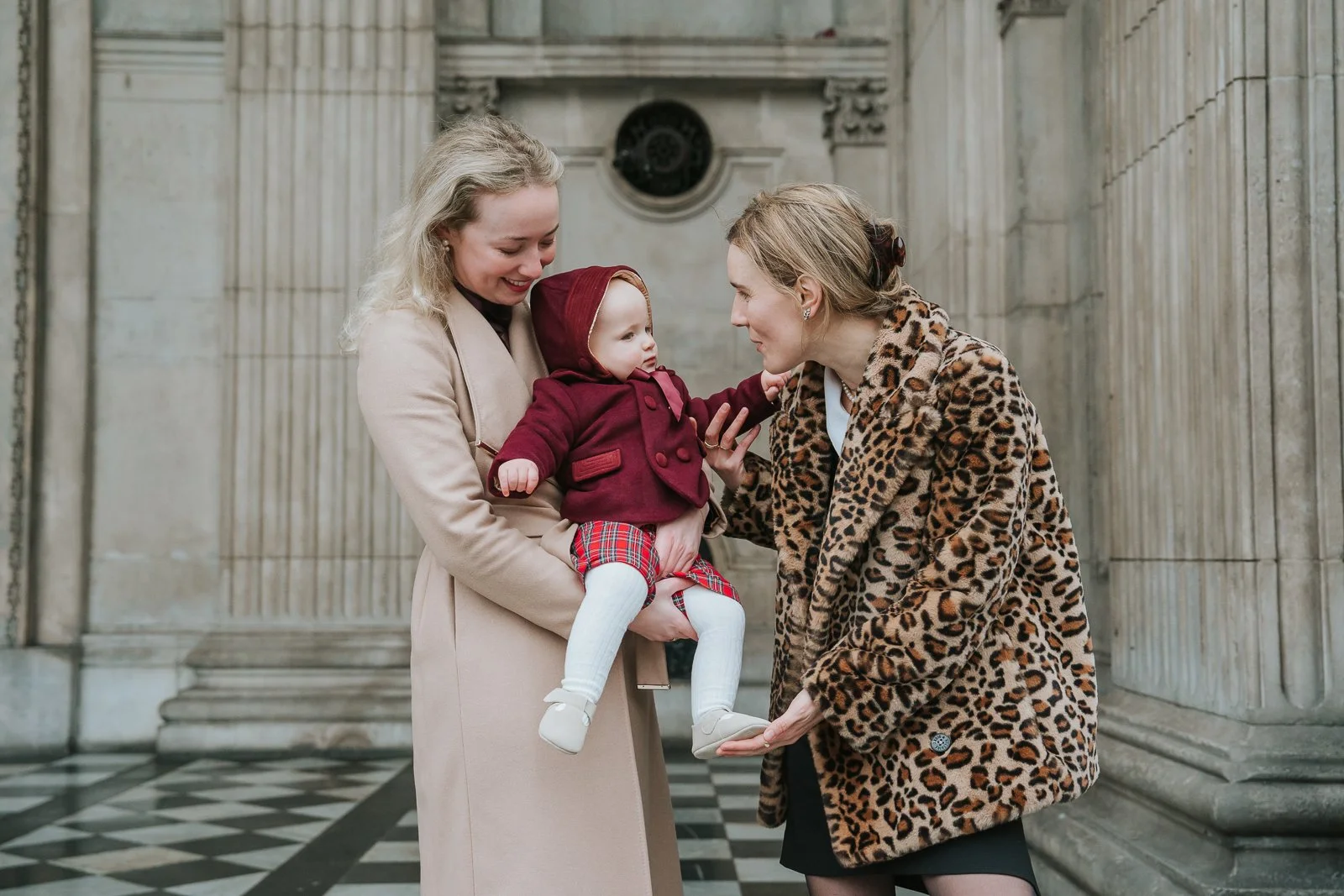  Candid moment of godparents interacting with a baby outside St Paul’s Cathedral during a christening photoshoot 