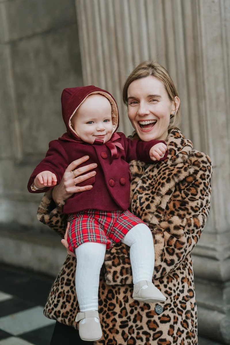  Smiling godmother holding a baby outside St Paul’s Cathedral after the christening 