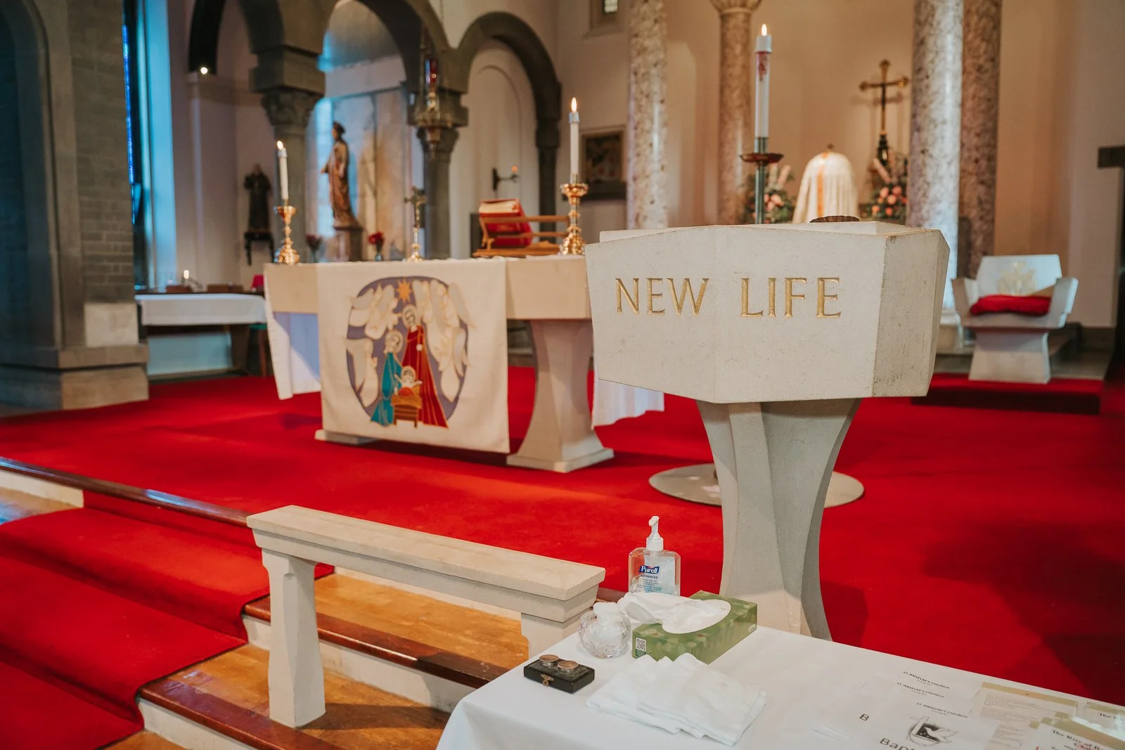  Baptism font with “New Life” inscription beside altar inside London Catholic church prepared for christening ceremony. 
