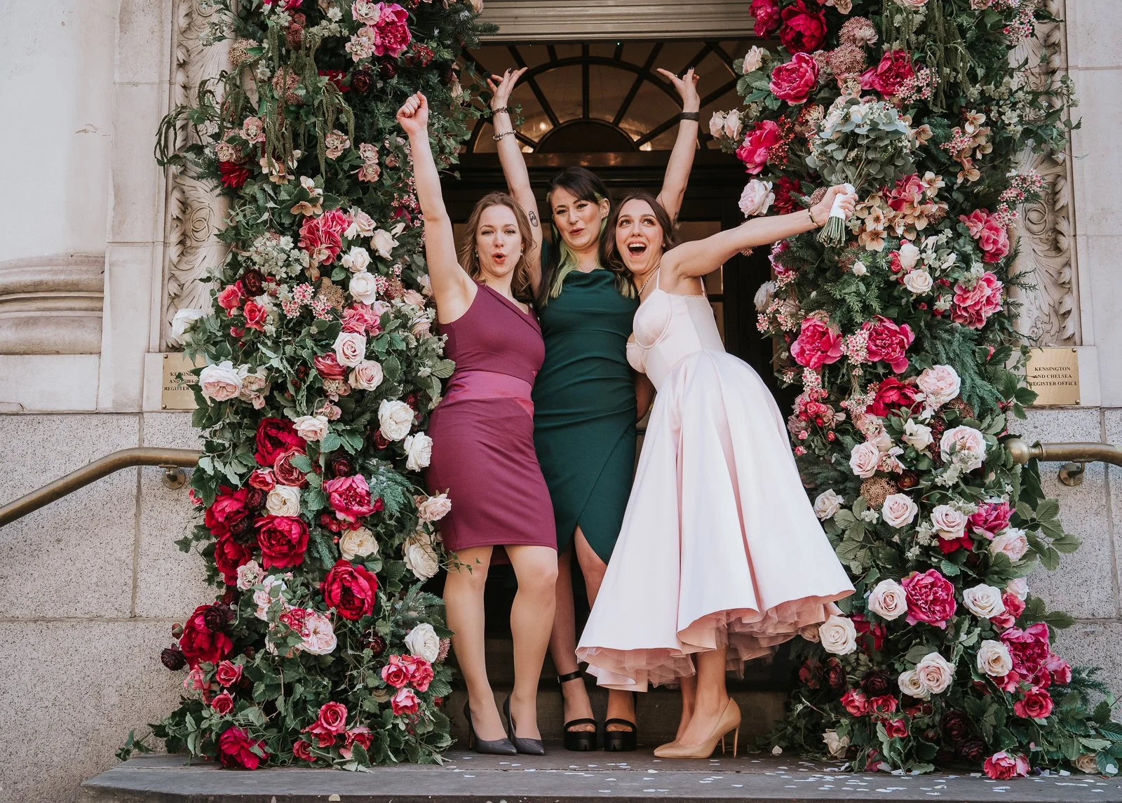  Bride celebrating with friends under the floral entrance after an intimate London civil ceremony 