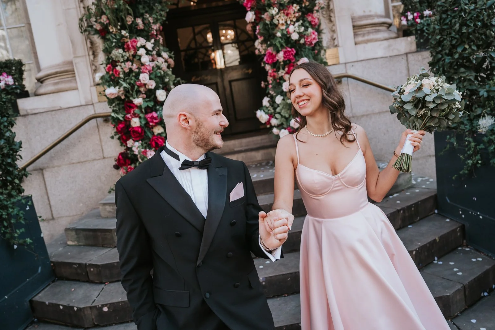  Newly married couple walking hand in hand outside after their intimate London civil ceremony 
