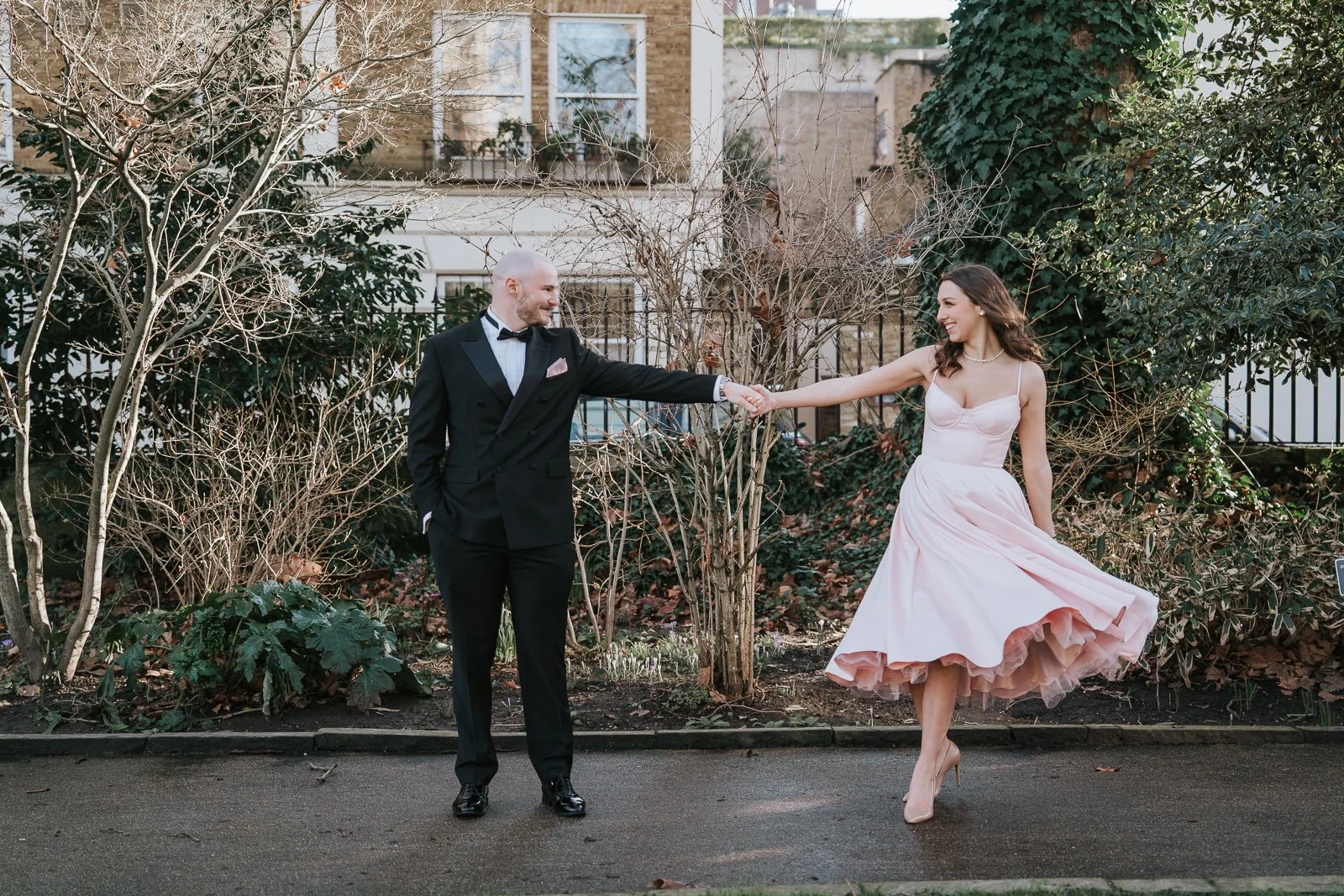  Couple laughing together while walking hand in hand after their small London wedding ceremony. 