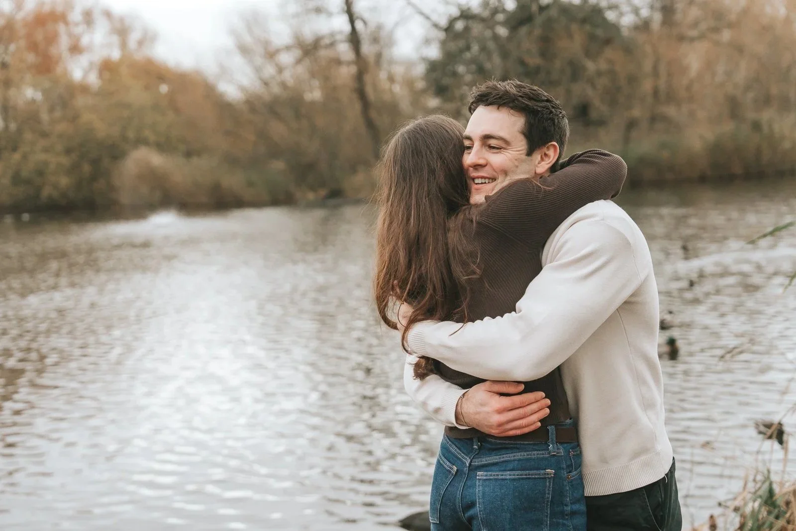   Emotional hug between newly engaged couple beside the pond at Clapham Common, South London. 