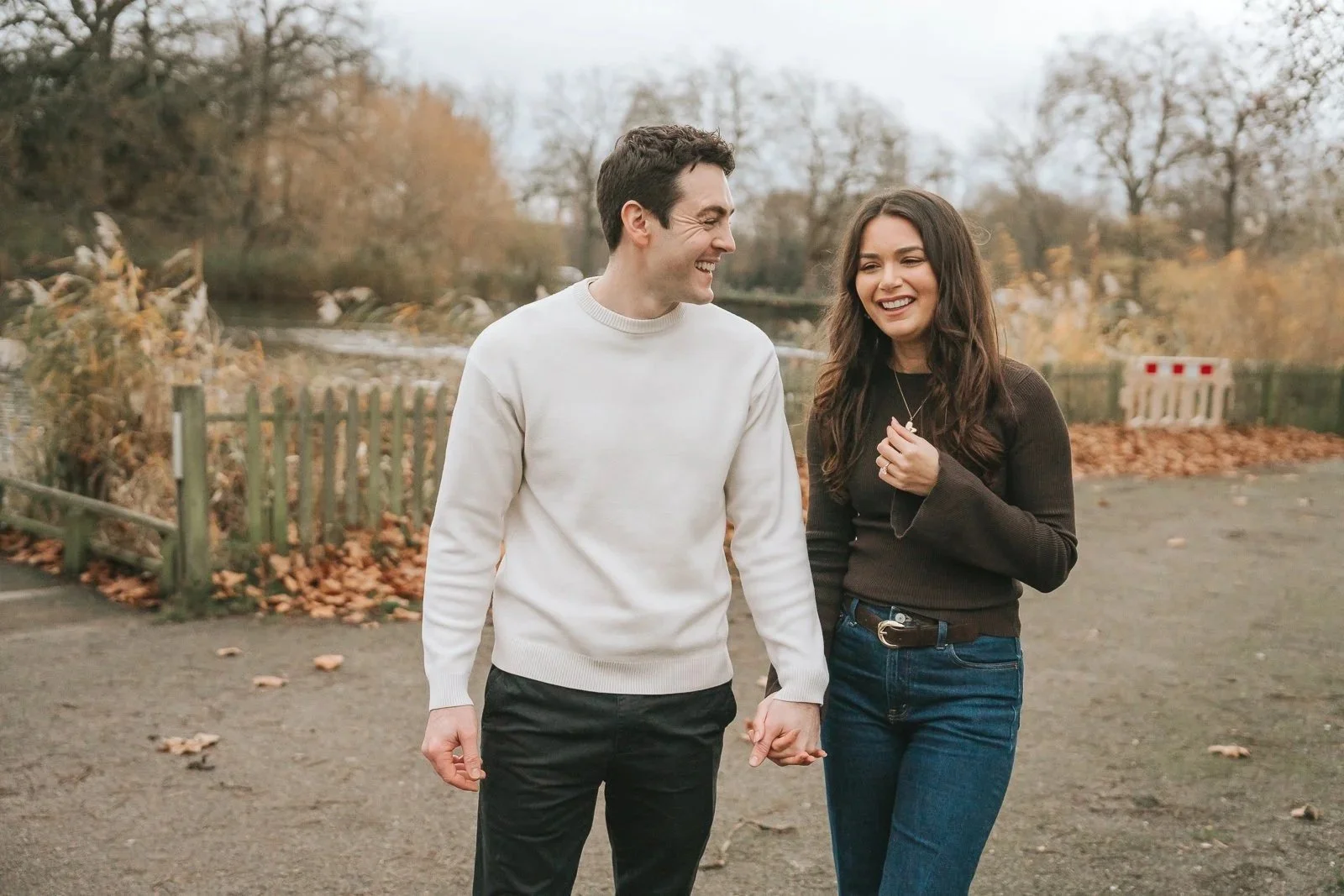 Happy engaged couple walking hand in hand through Clapham Common in autumn after London proposal. 