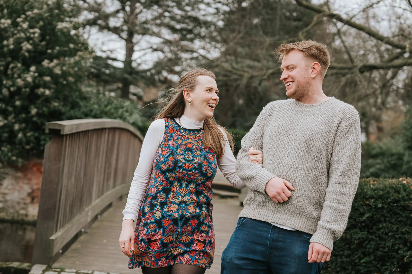 Engaged couple walking hand in hand across the wooden bridge at Eltham Tudor Barn, natural pre-wedding photography in the gardens of this South East London wedding venue. 