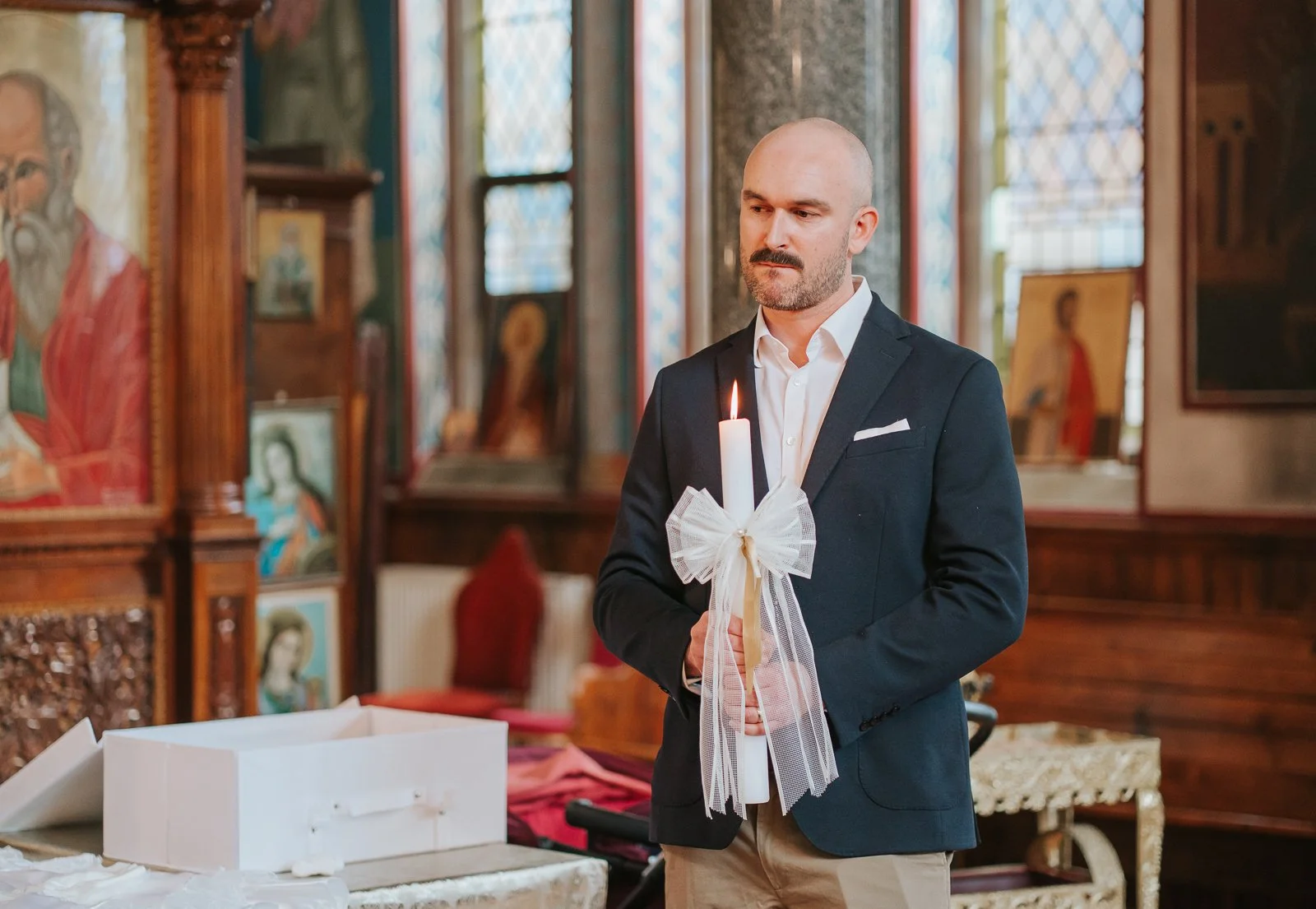  Godfather holding decorated baptism candle during a Greek Orthodox baptism at St Constantine &amp; St Helen, Crystal Palace SE19. 